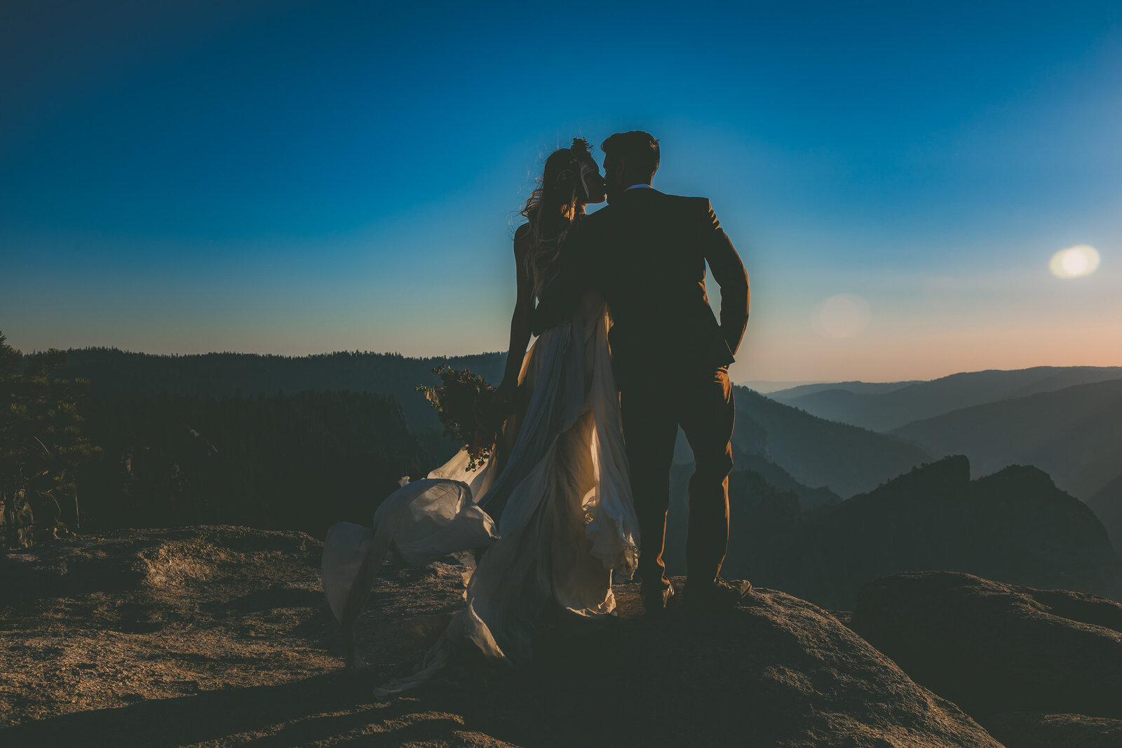 A silhouette of a bride and groom as they kiss at Taft Point in Yosemite.