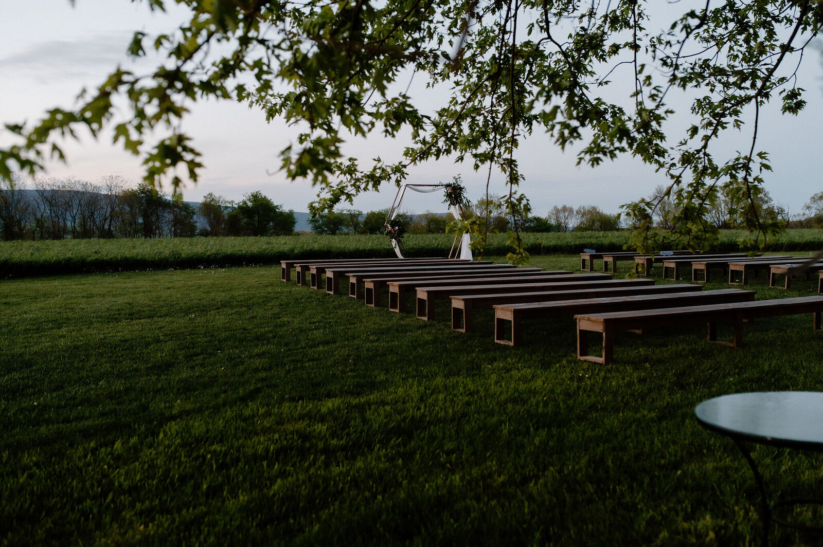 wedding ceremony setup with benches in lush green field Heritage Restored venue