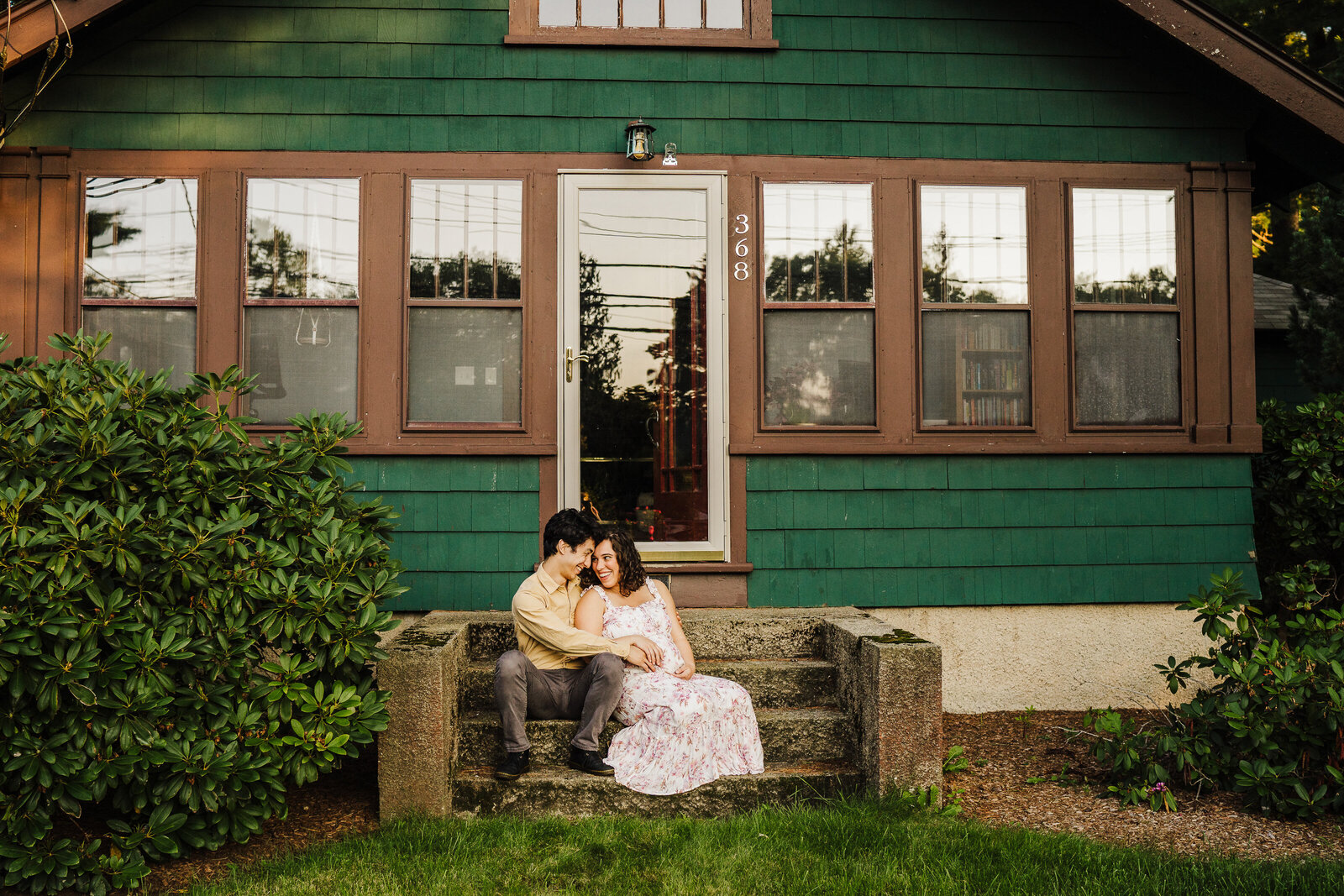 expectant couple sits on front steps
