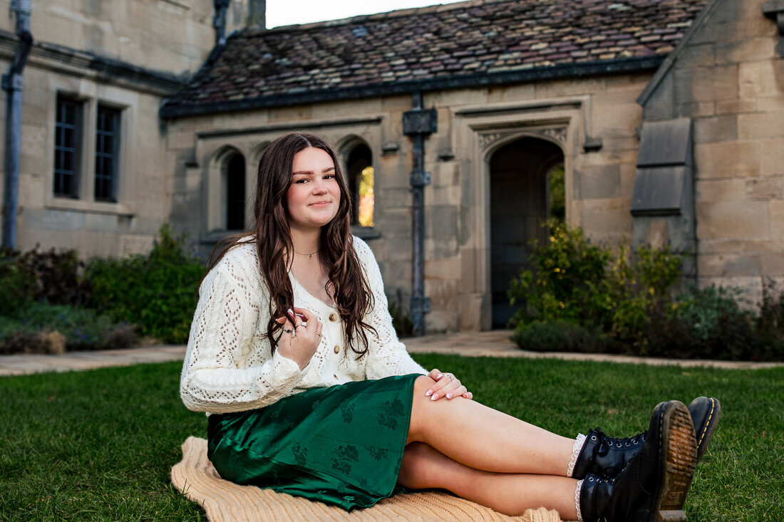 A senior student from North Allegheny School district sits on a blanket in the grass in front of the heartwood acres mansion.