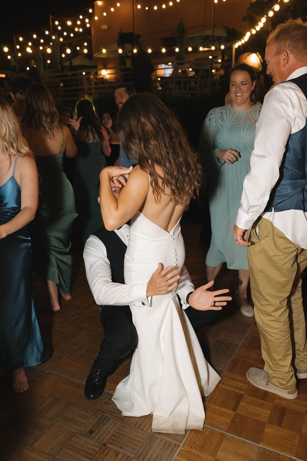 Bride and groom dancing under string lights at night