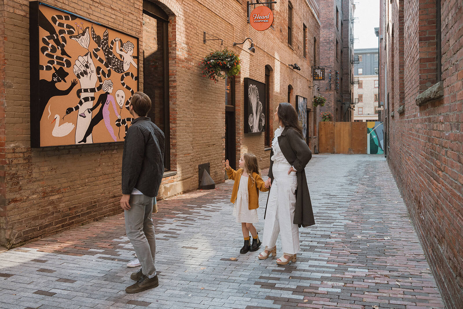 family of four standing in alleyway looking at art with kids