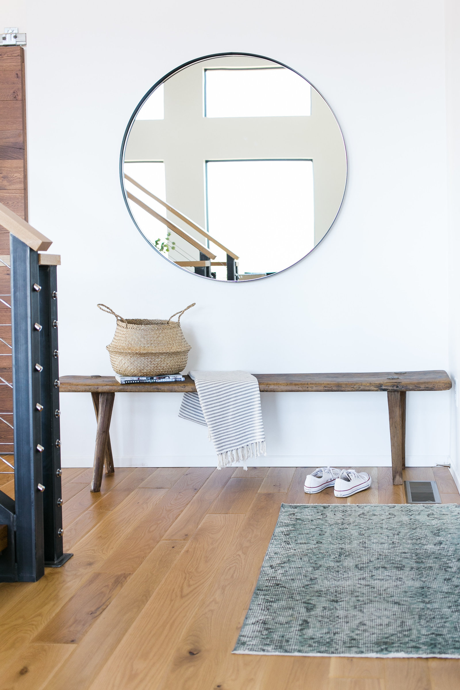 Modern, minimalist entryway with round mirror and reclaimed, antique bench