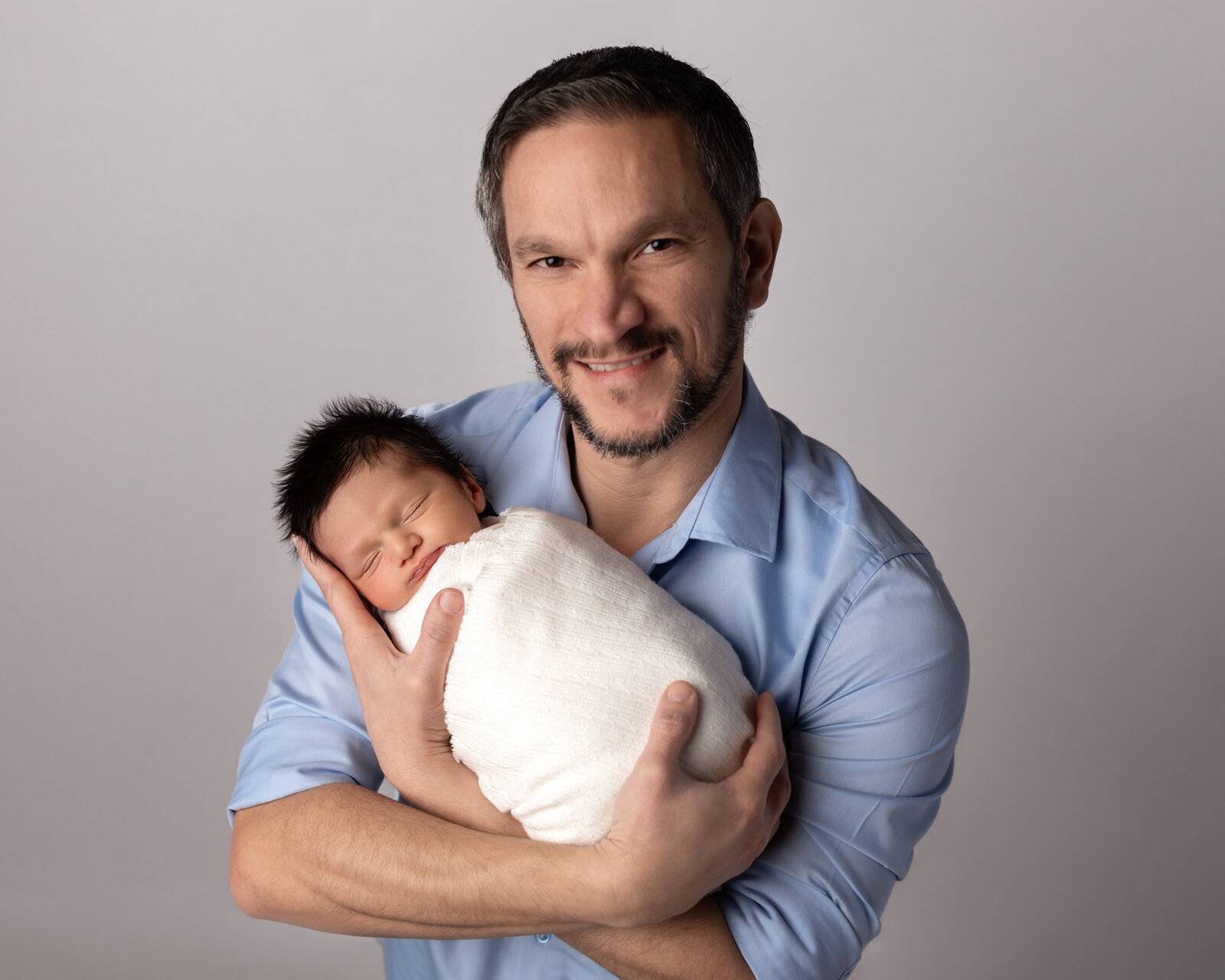 dad holding newborn baby boy for studio portrait
