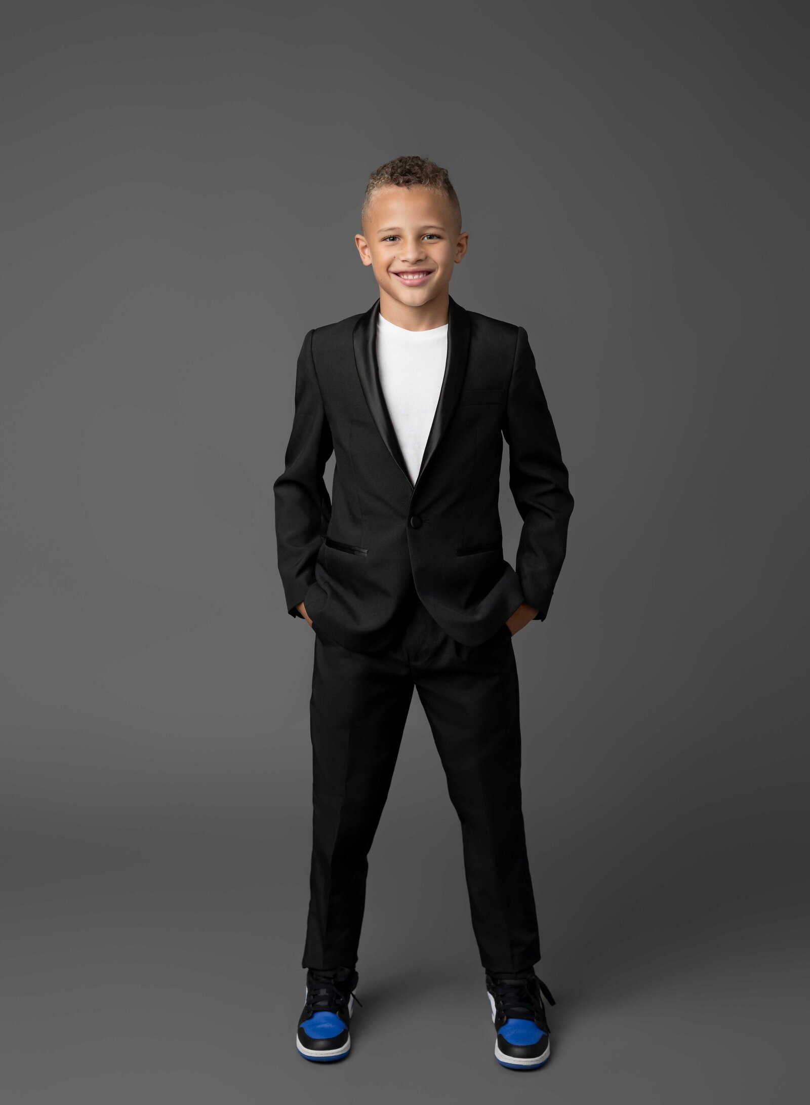 Boy dressed in black suit with hands in pocket. Family photo taken at Atlanta Photo Studio by Jenni Nikki Photography.
