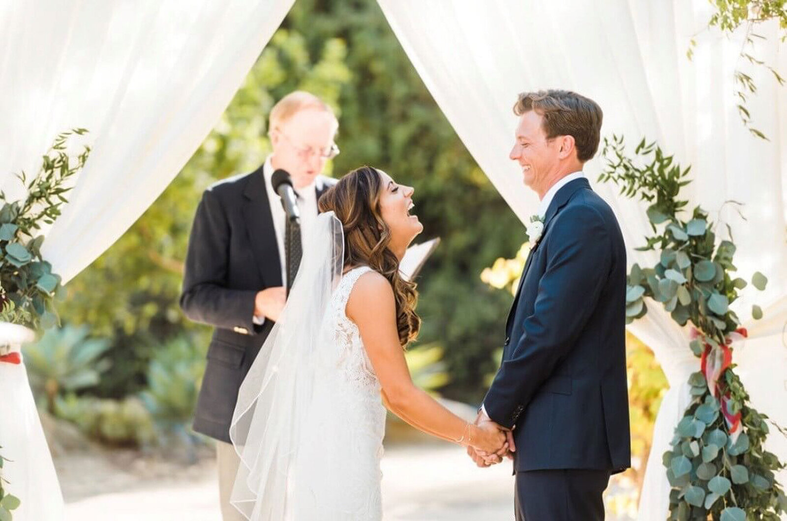 Bride and groom standing at altar. the bride is laughing and the groom is smiling