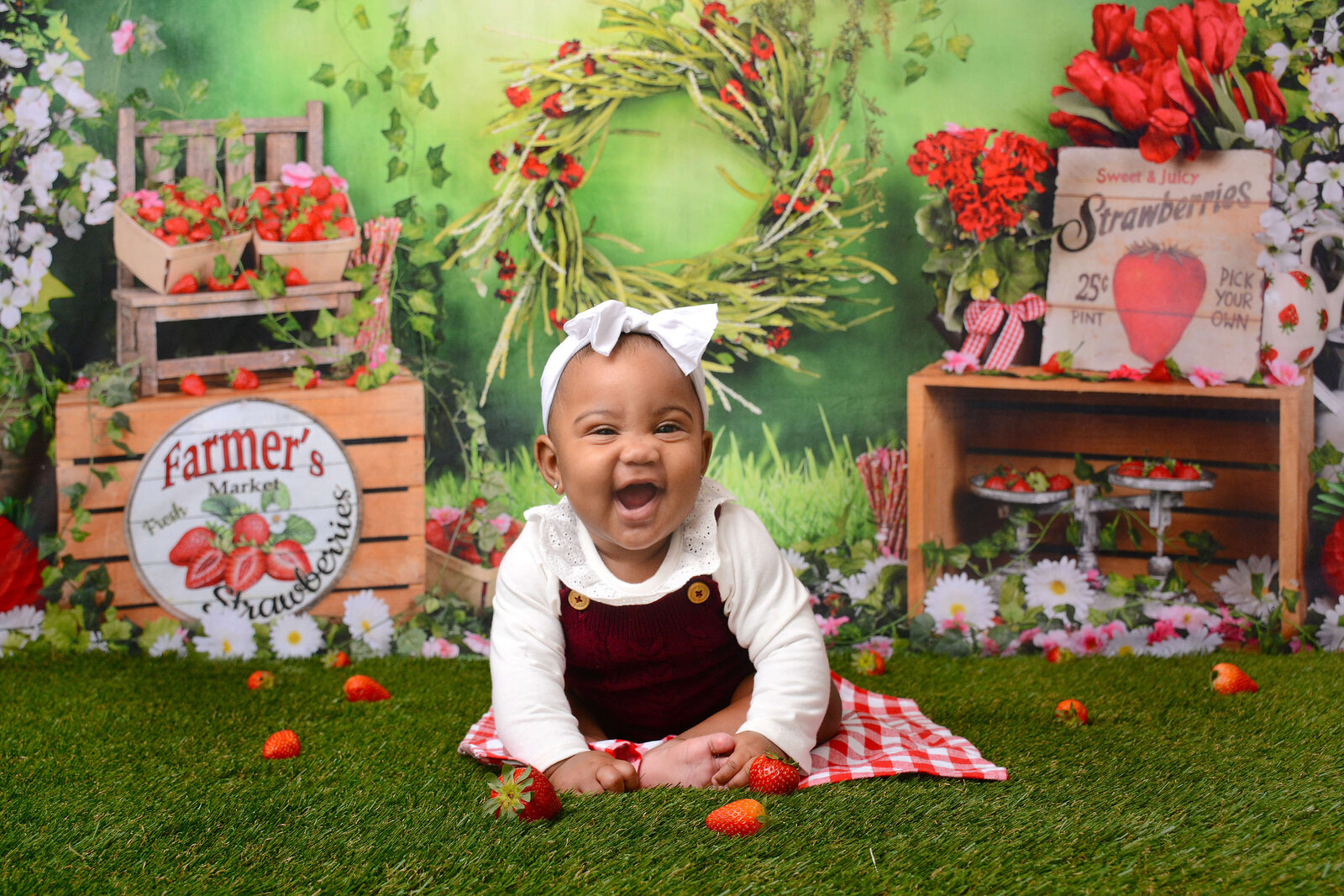 6 month old baby girl smiles at her strawberry themed photoshoot