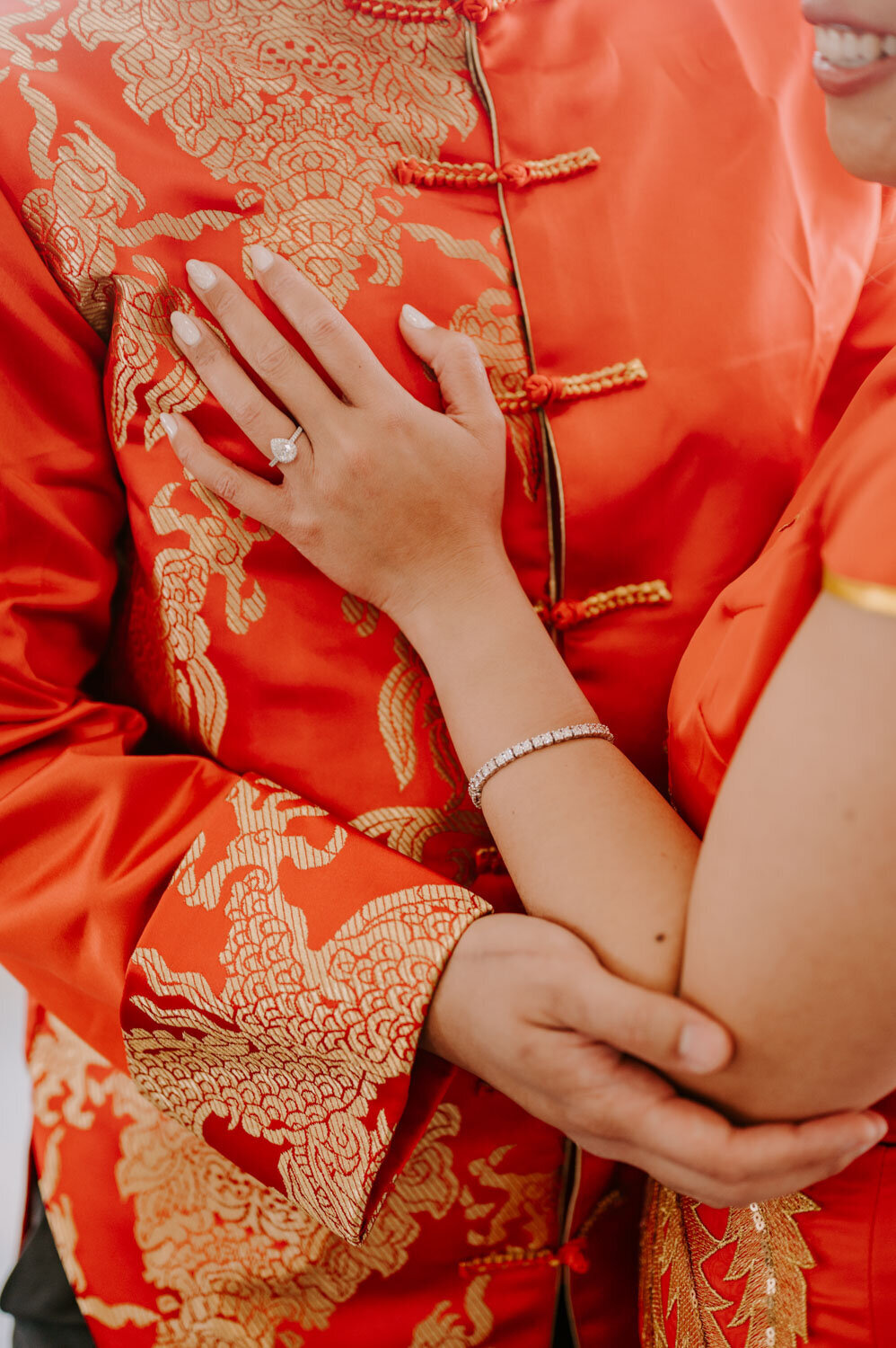 Close-up of couple’s hands in traditional red attire