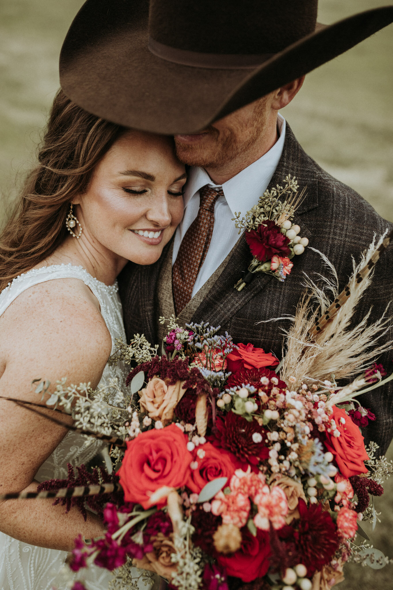 texas groom with bride holding red and pink bouquet