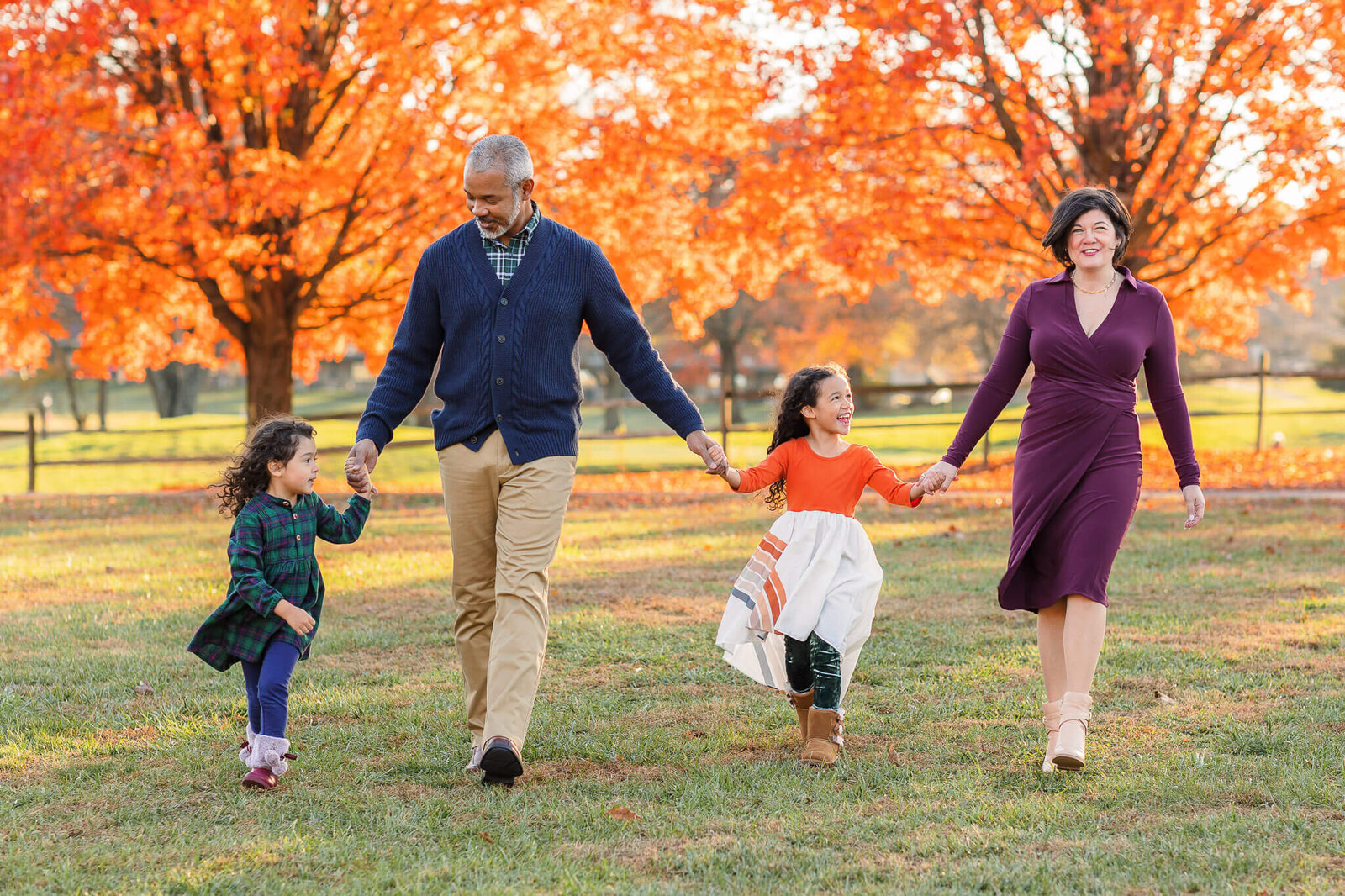 A family walking with fall foliage behind them