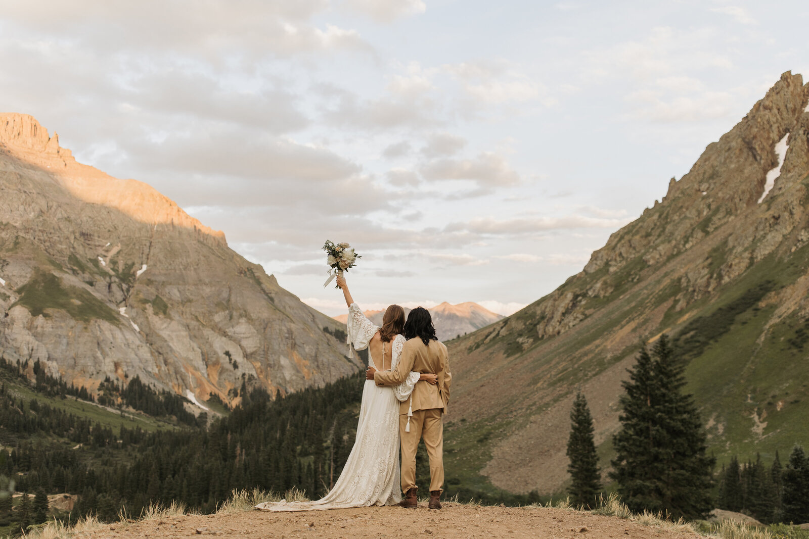 wedding couple admires mountain views with arms wrapped around each other after eloping in Colorado 