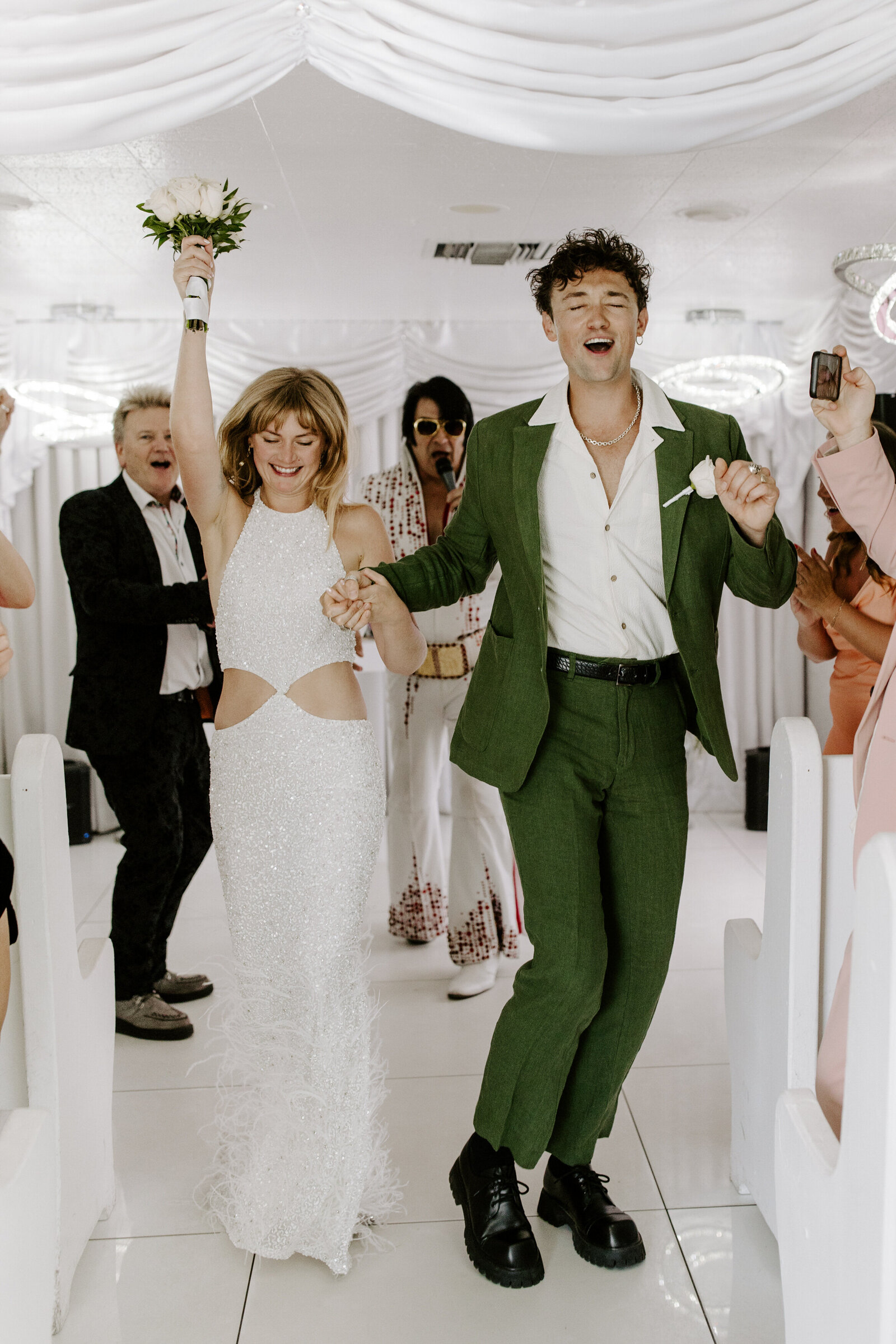 A newlywed couple dancing as they walk back up the aisle 
