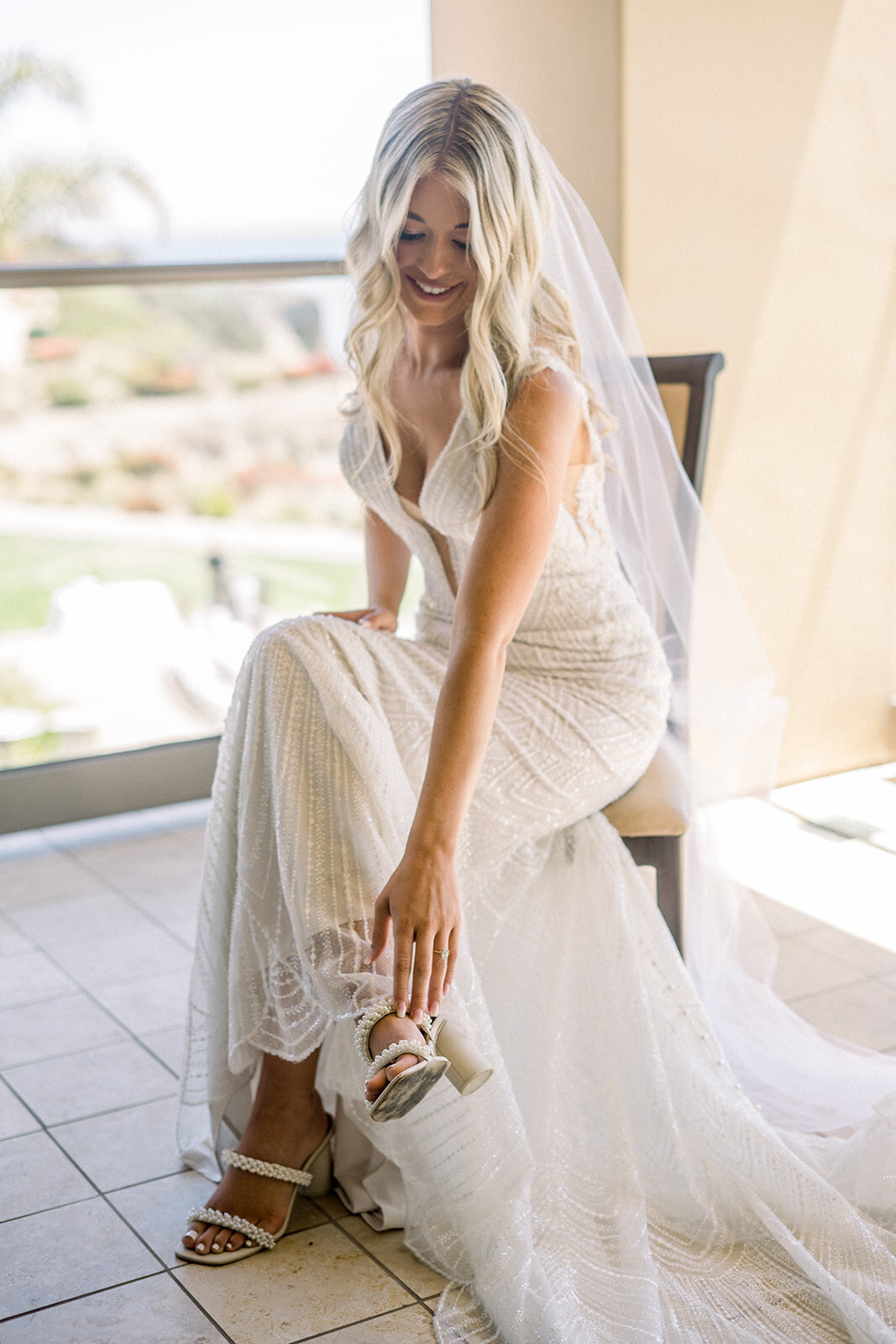 Bride puts on wedding heels at Dolphin Bay Resort in Pismo Beach, CA