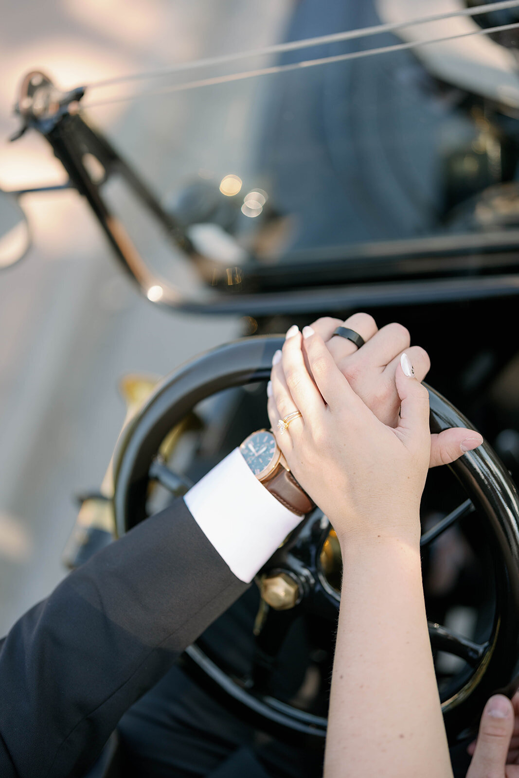 Close-up of newlyweds holding hands in a vintage car after their Michigan wedding, captured by editorial wedding photographer Raechel Marie.