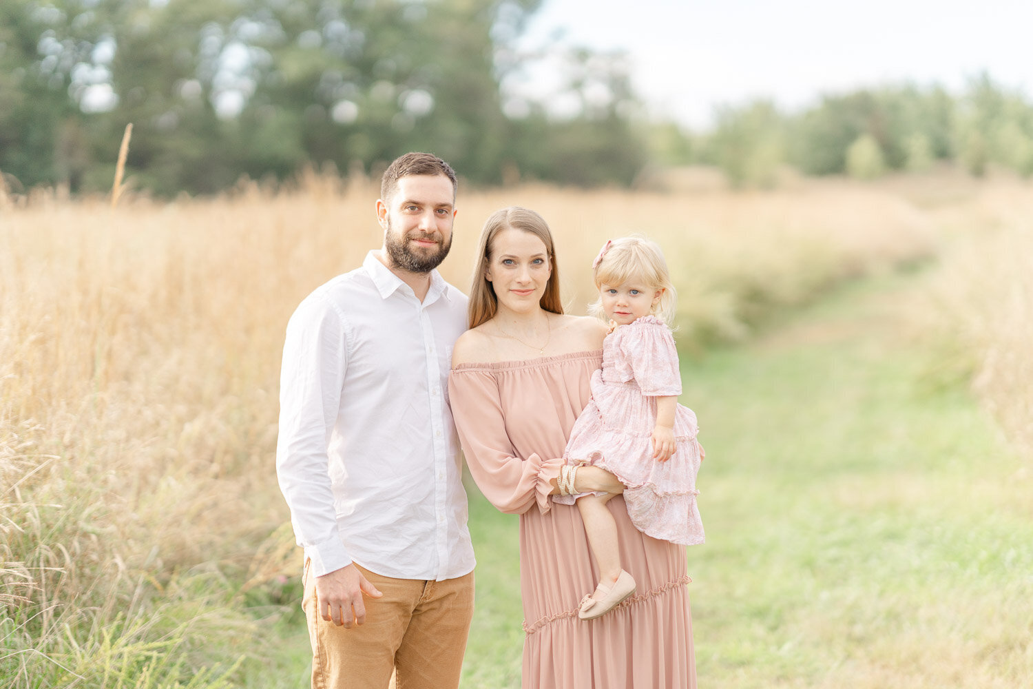 family posing in a field of tall grass during minis in Ashburn, Virginia