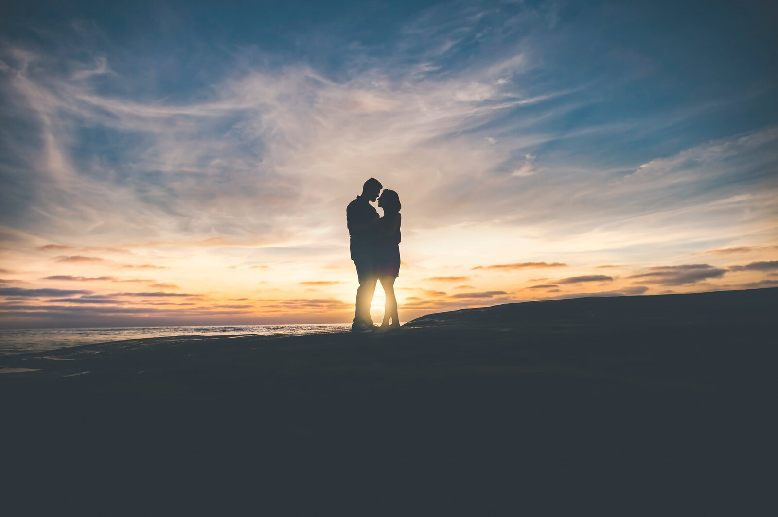 Bride and groom facing each other with sunset