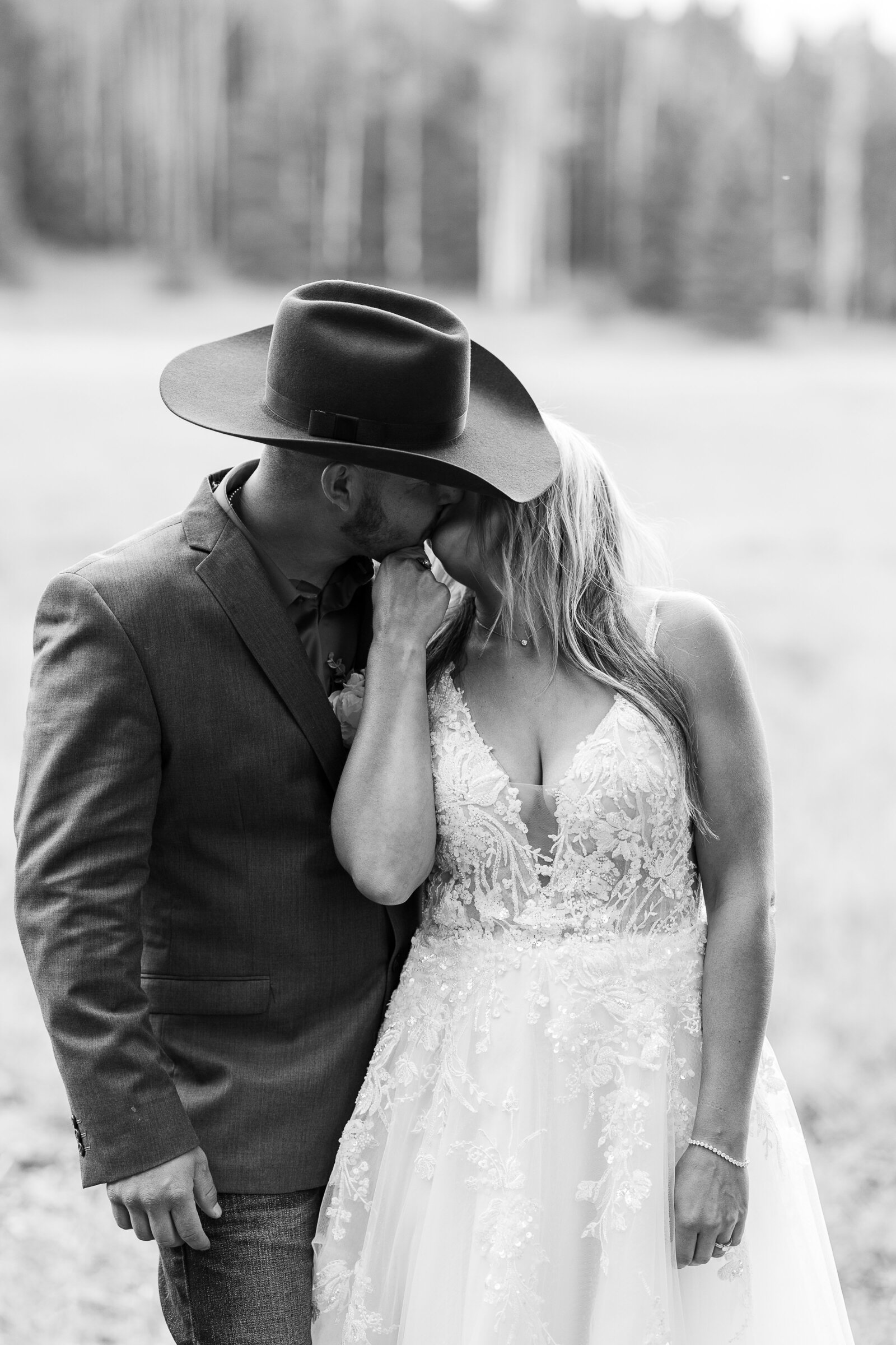 Bride holds grooms chin and gently kisses him in this artistic sweet capture
