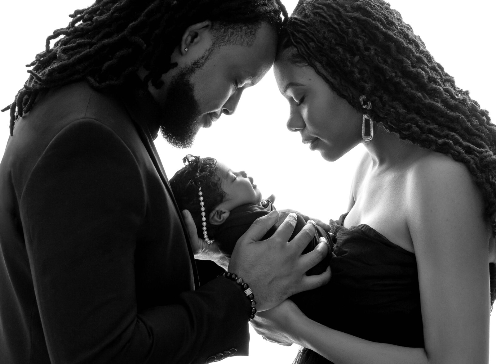 B&W professional portrait of Mom and Dad looking at baby lovingly. Photographed by Jenni Nikki Photography at Marietta Newborn Photo Studio.