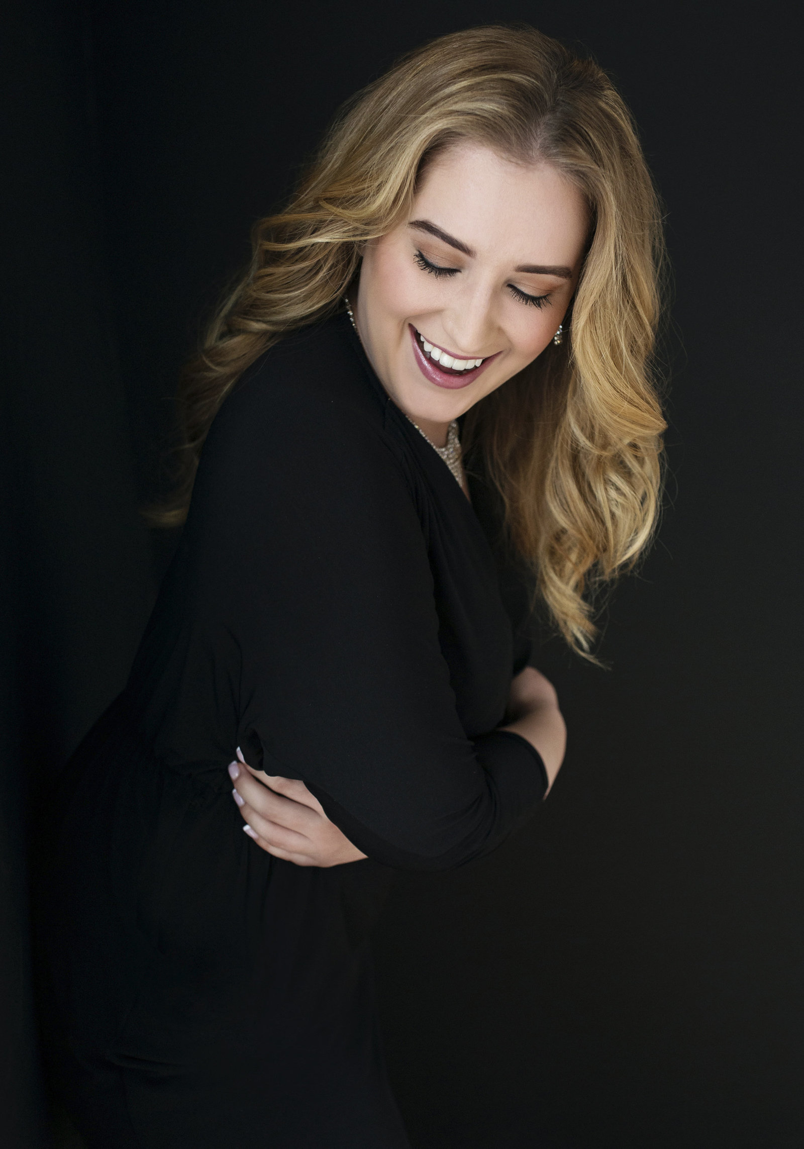 modern  luxury realtor Portrait Photo of a blonde woman hugging herself and smiling  wearing black dress