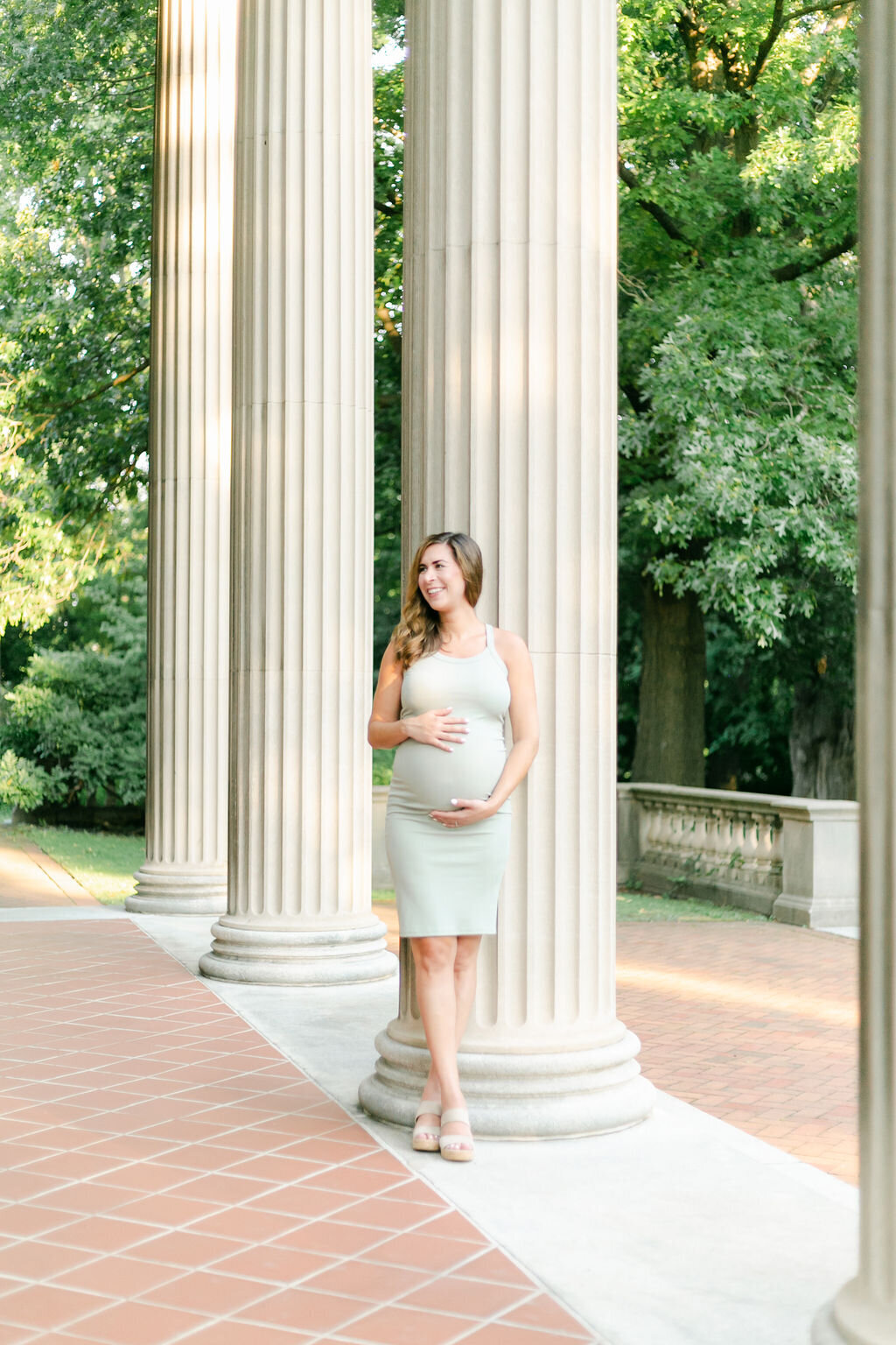 A pregnant woman caresses her belly during a Rochester NY maternity photography session at the George Eastman House.
