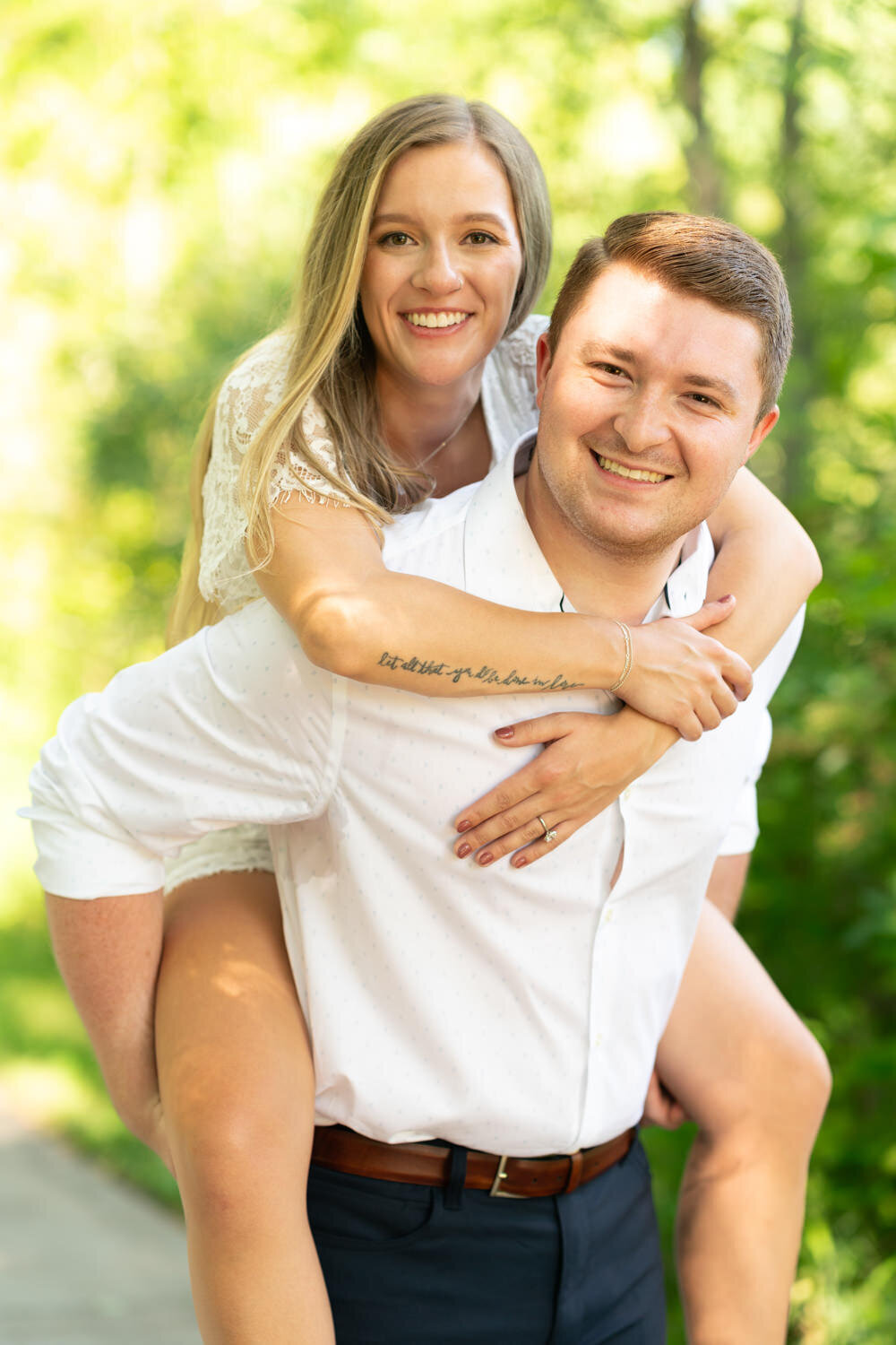 Man carries woman dressed in white romper on his back.