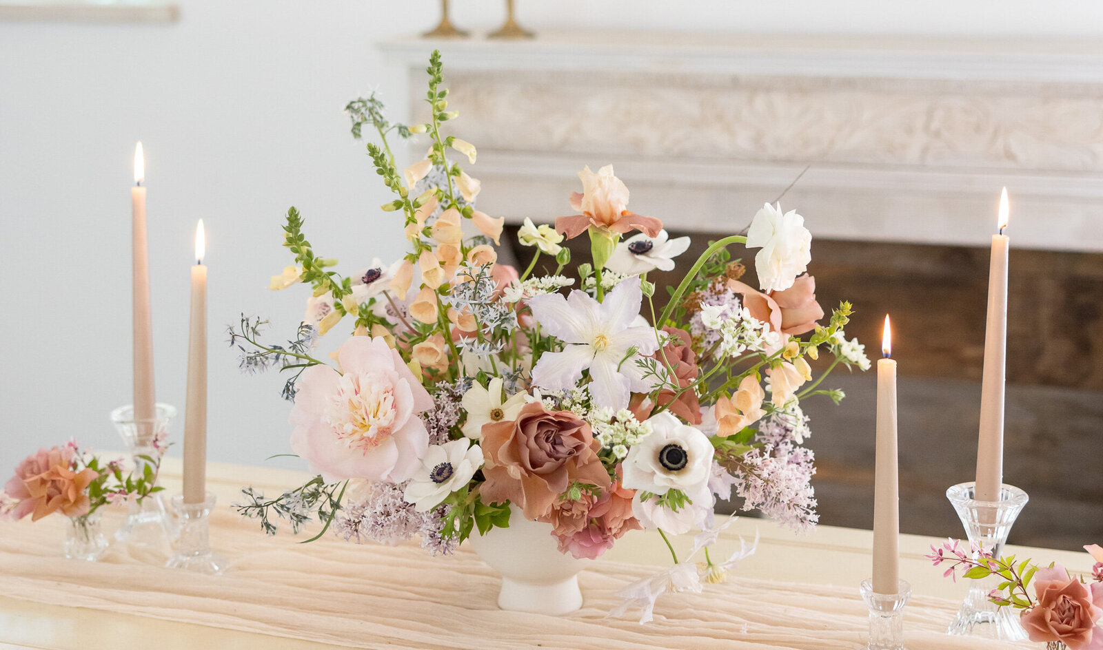 Low centerpieces with soft muted pastel spring flowers with taper candles