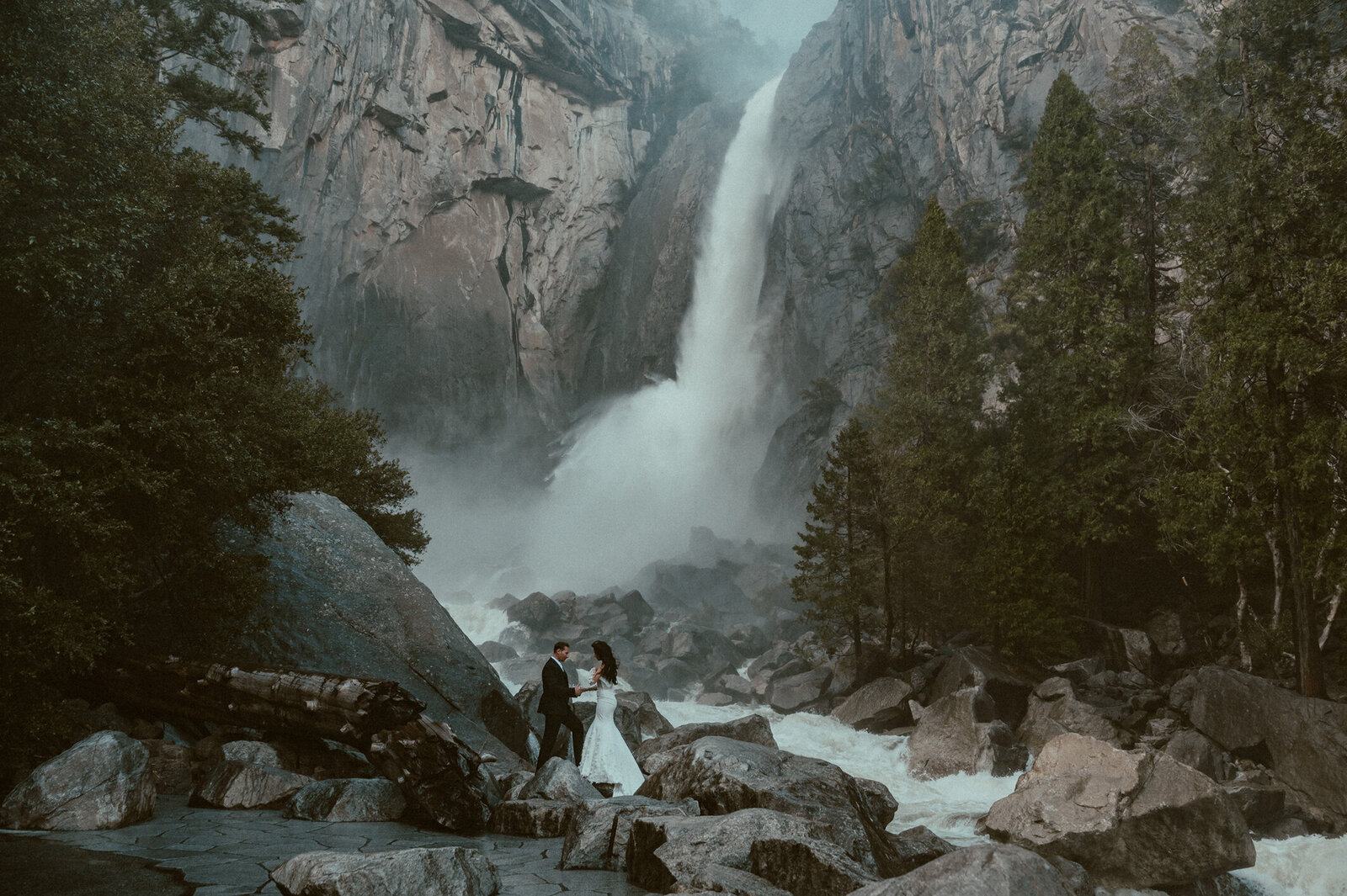 bride and groom at the base of yosemite falls at their destination elopement in Yosemite national park
