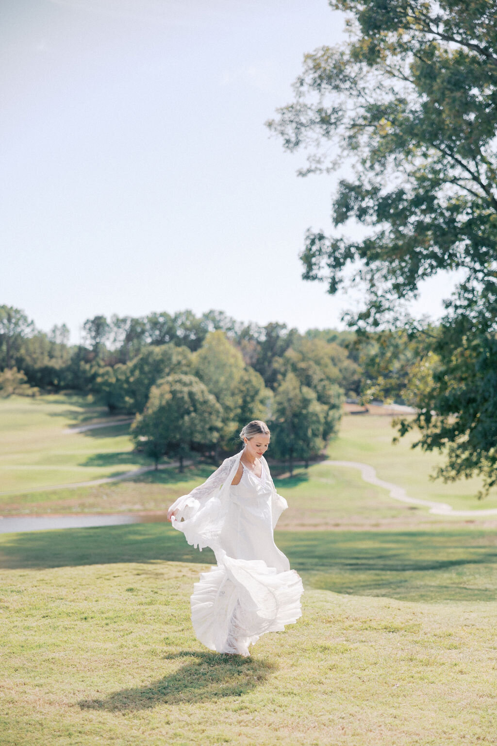 Bride in white robe runs on golf course at Chimney Oaks