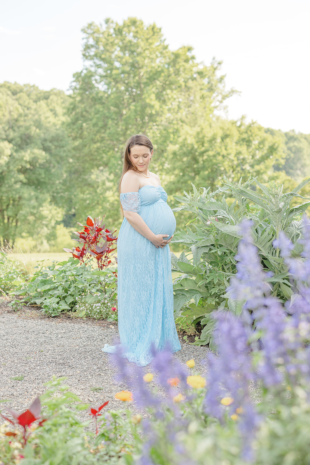 expecting mom looking over her shoulder taken at a garden in spring by TBP, a maternity photographer in Reston, VA