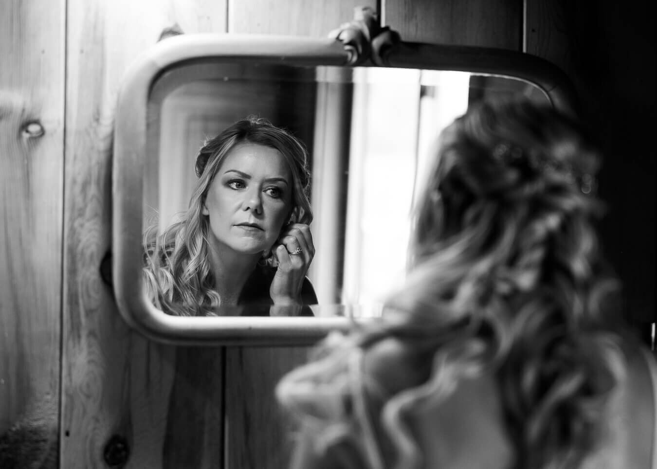 Bride Looking in mirror putting in earring