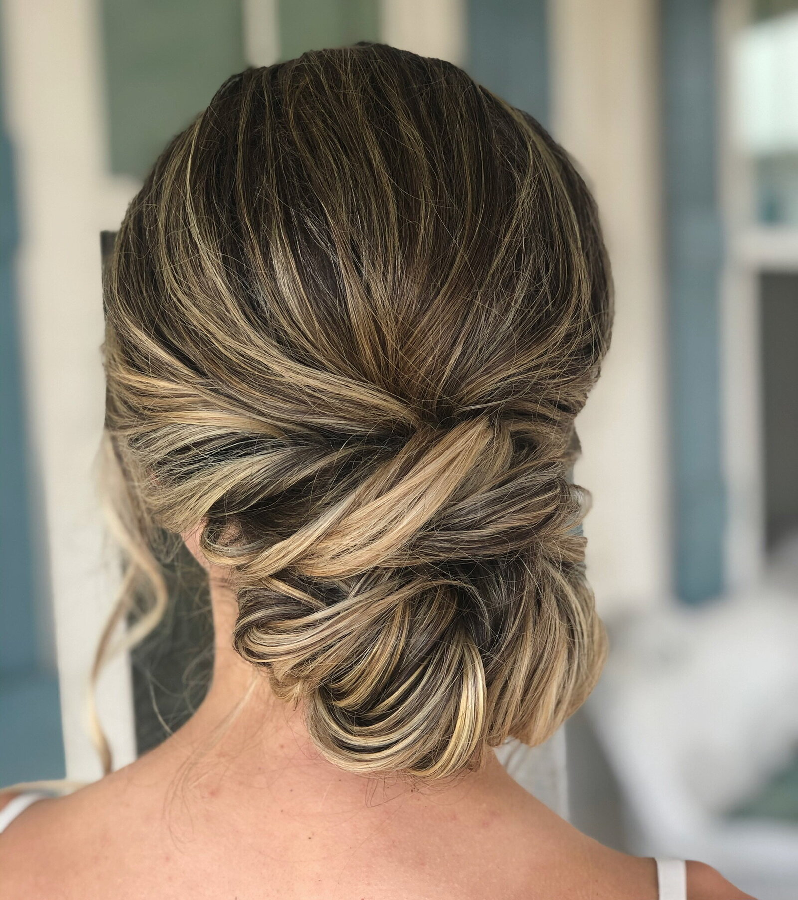 Experience the epitome of bridal beauty with an elegant updo, showcasing soft blonde highlights and intricate twisted detailing. Perfect for your special day in Texas, this hairstyle embodies sophistication and grace, complementing the complete bridal hair and makeup process seamlessly.