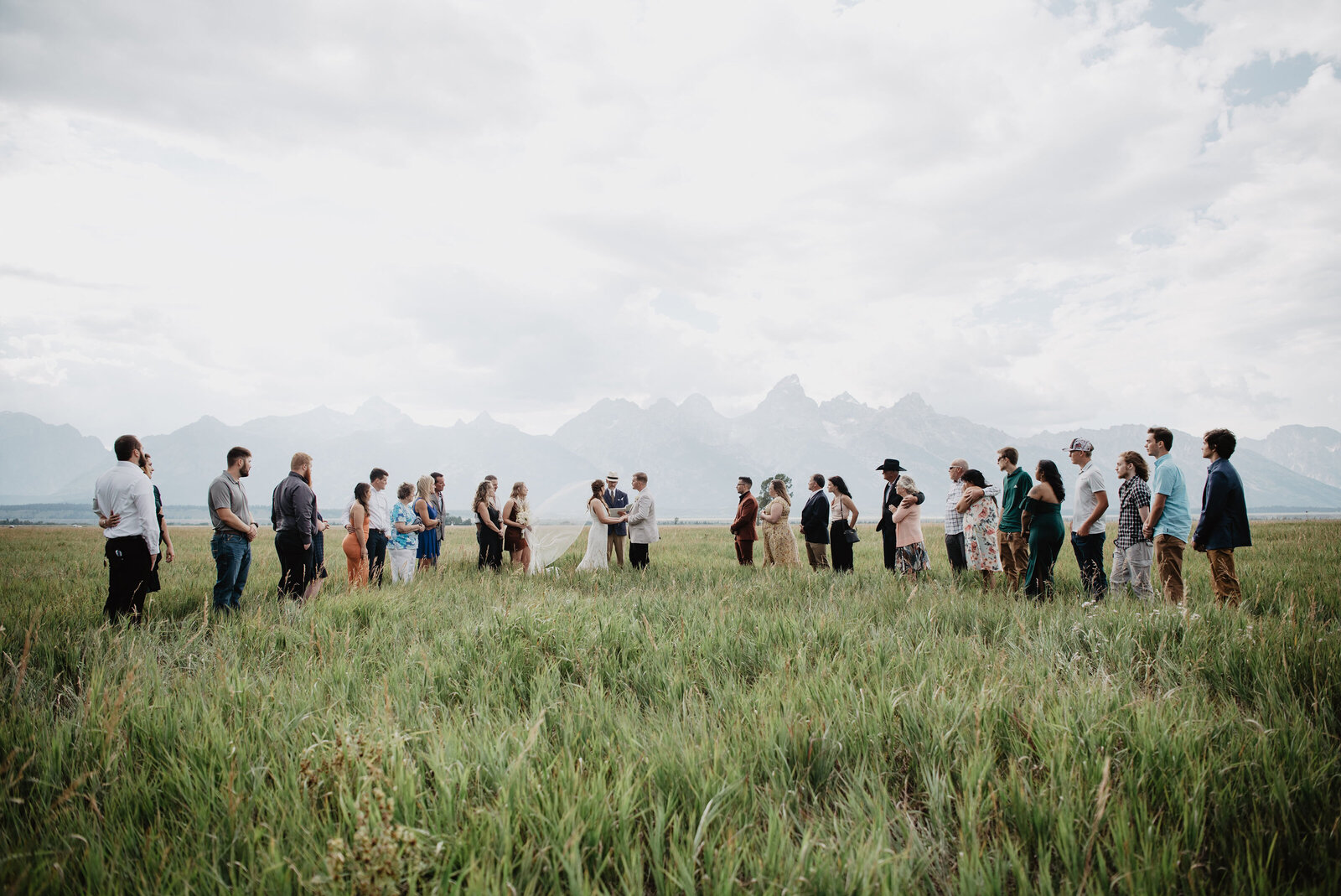 jackson hole wedding at mormon row with couple getting married surrounded by their family and friends with the tetons in the distance captured by jackson hole wedding  photographers