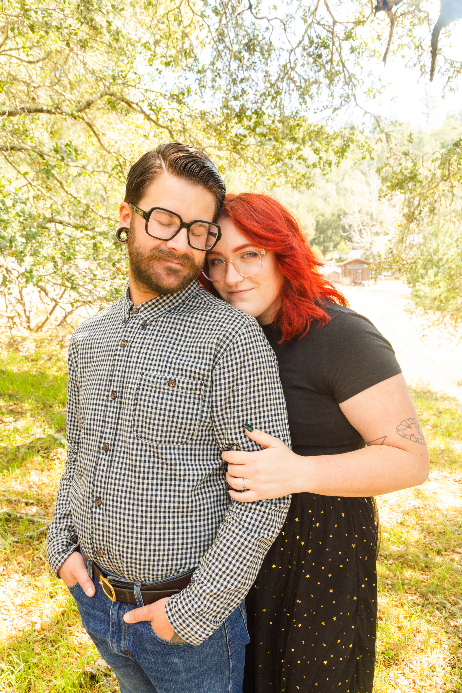 An tattooed engaged couple poses for photos in a redwood forest in Santa Cruz, Ca.