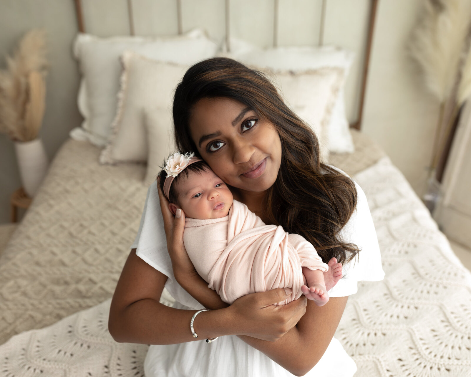 mom holding newborn baby girl wrapped in pink for studio portraits cleveland newborn photographer
