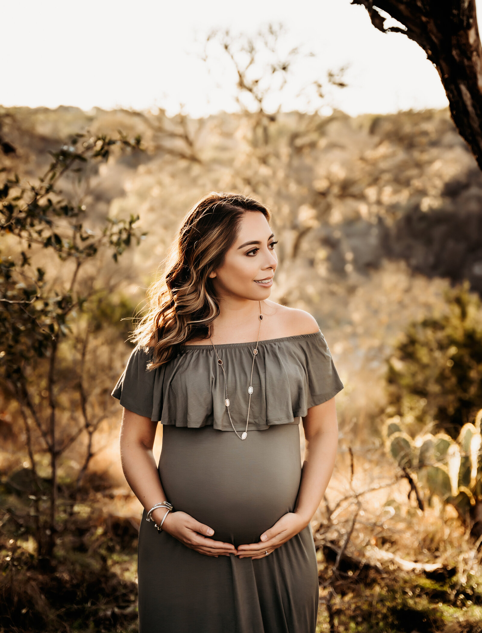 Maternity Photographer, an expectant other holds her belly outdoors and smiles