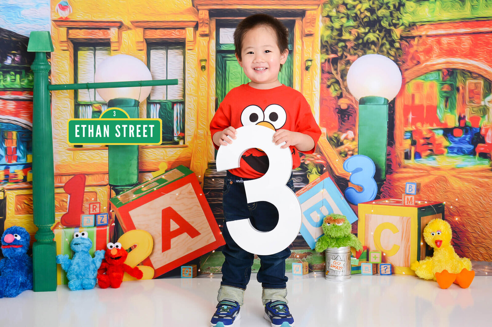 boy smiles while holding a 3 at his birthday photography shoot