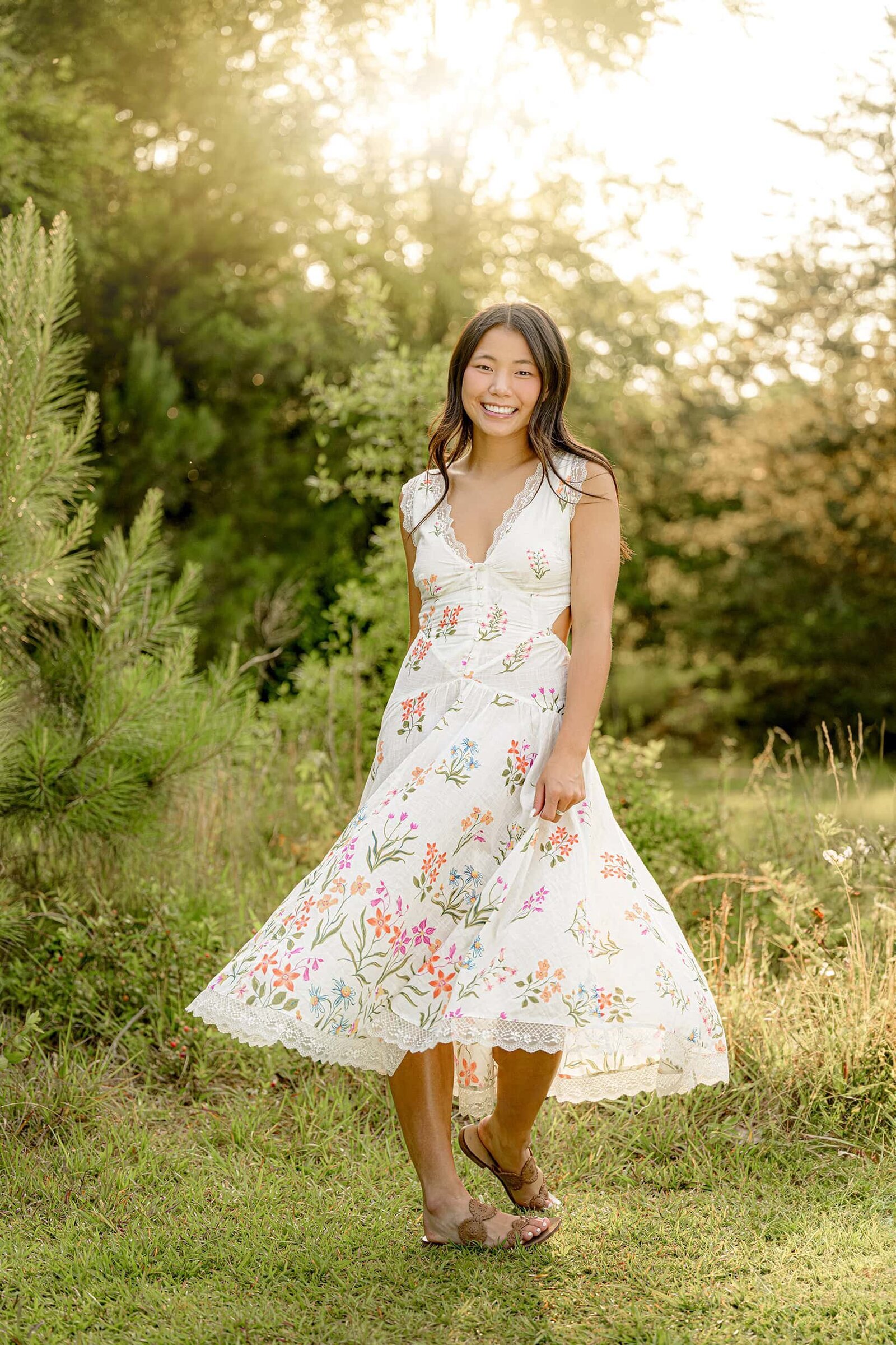 Reagan a Cuthbertson High Senior wearing white jeans and a black top posing with her hands in her pockets standing by a weathered wooden building