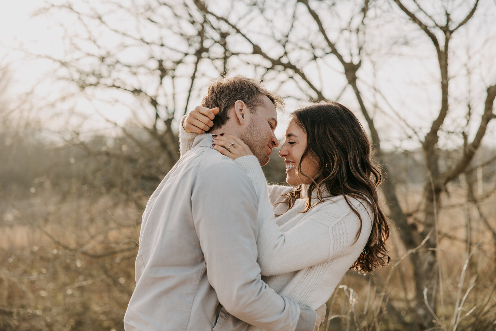 Couple on dirt road surrounded by trees, woman gently touching man's hair, ready for a kiss, romantic moment.