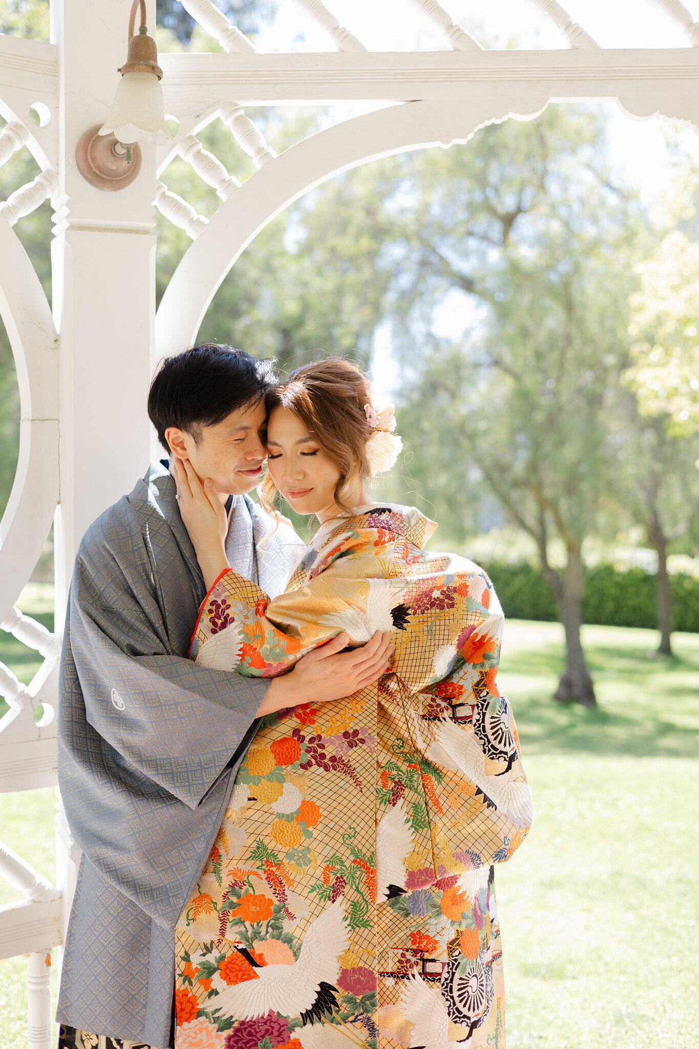 Tender moment of a bride and groom embracing under soft daylight at Brand Park Glendale, wearing elegant wedding kimono, kimono rental in Los Angeles | ロサンゼルスBrand Park Glendaleで柔らかな日差しの下、抱き合う着物レンタル花嫁と新郎