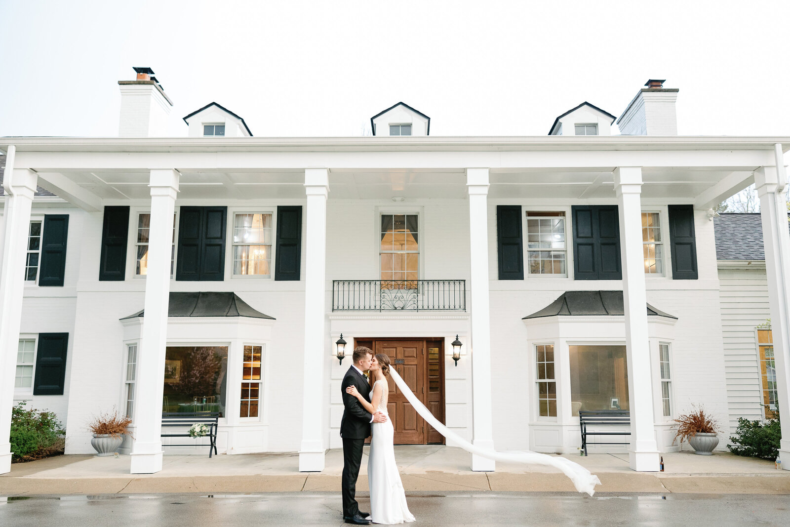 couple kissing in front of black iris estate wedding vneue