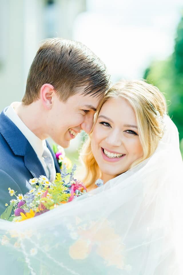Vibrant floral bouquet with smiling wedding couple