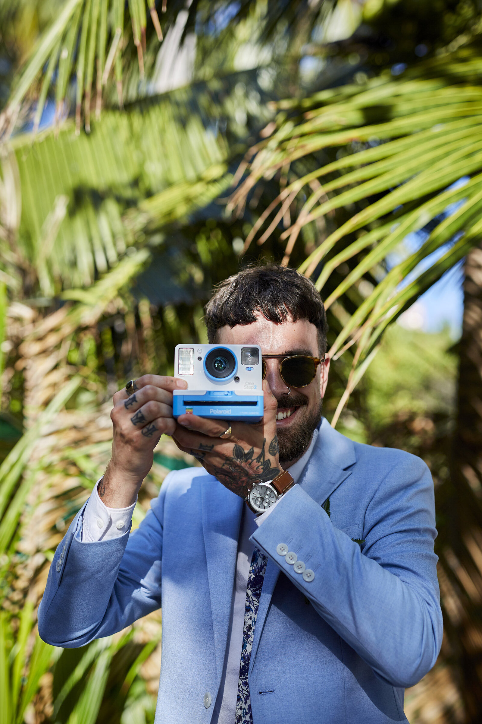 Groom holding polaroid camera
