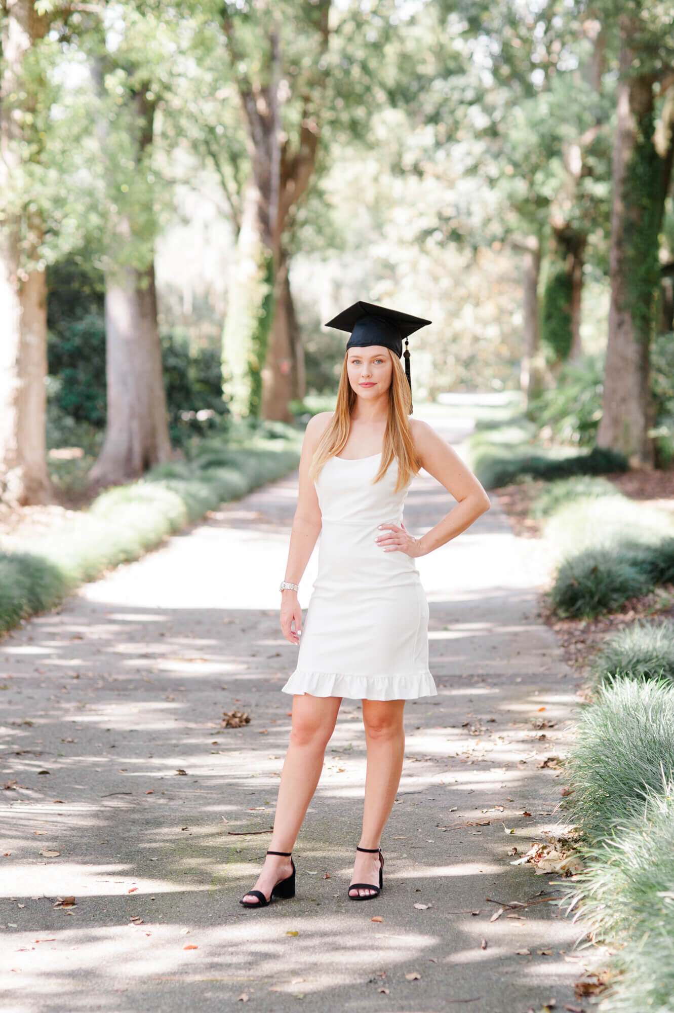Senior stands with hand on her hip and cap on during her senior session at Leu Gardens