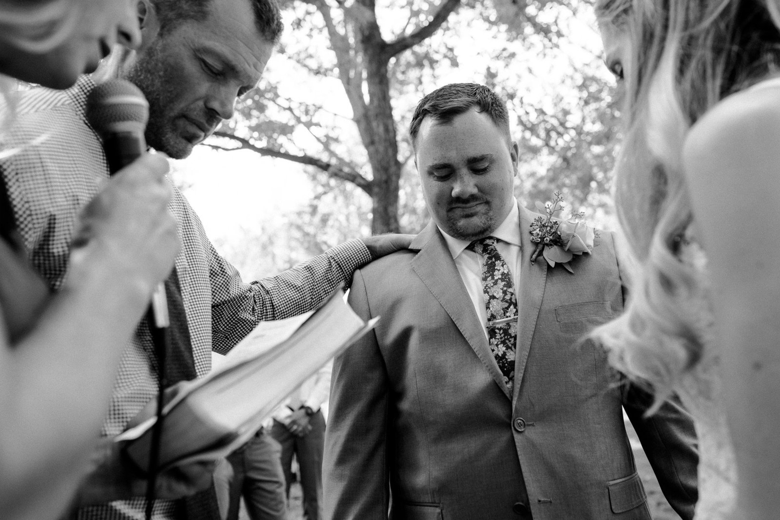Block one events wedding photographer in old town fort collins. Black adn white of groom praying with groomsmen.