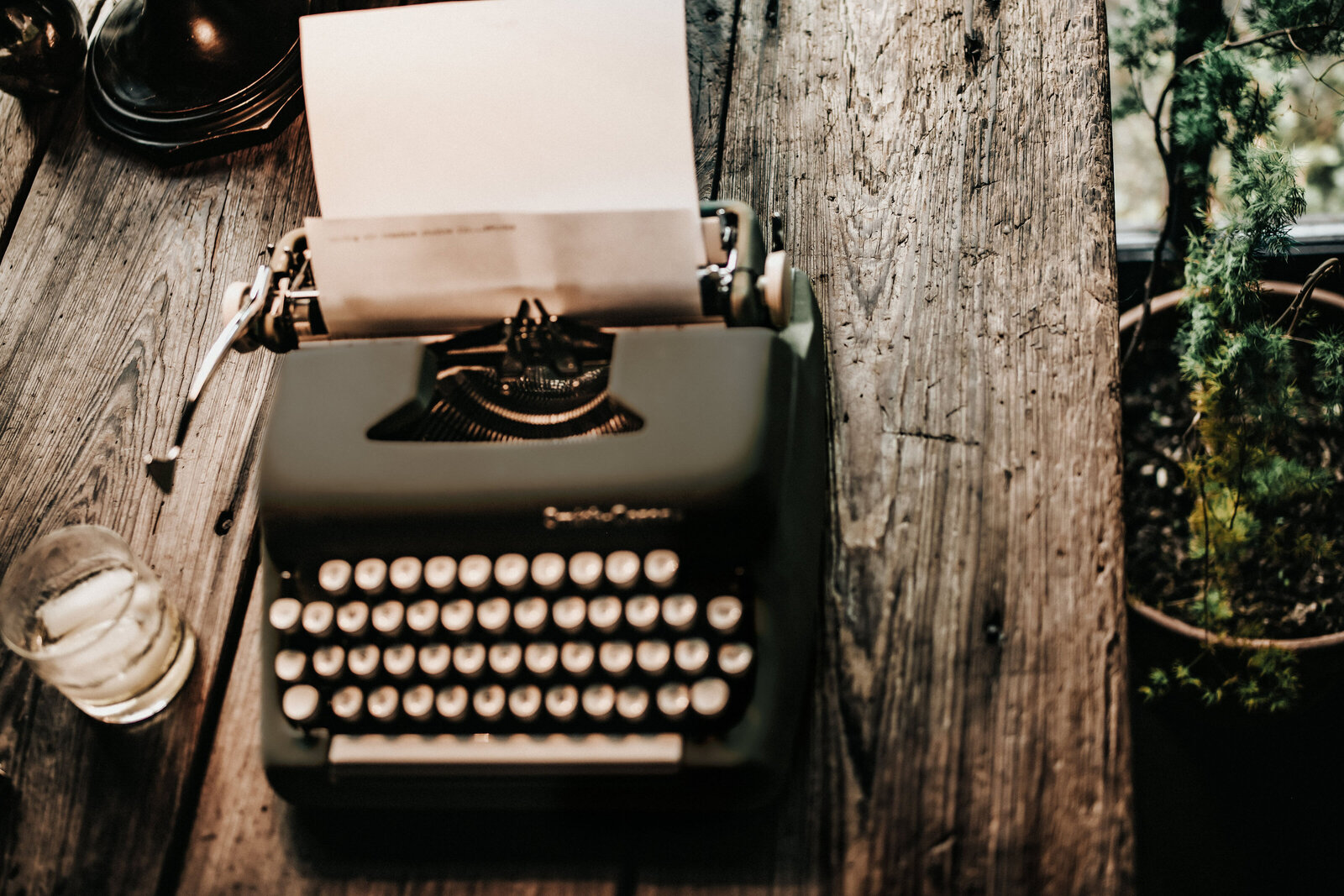 BYOBrand Blog - Entrepreneur Posts Image : Green Vintage Typewriter on table next to whiskey on the rocks