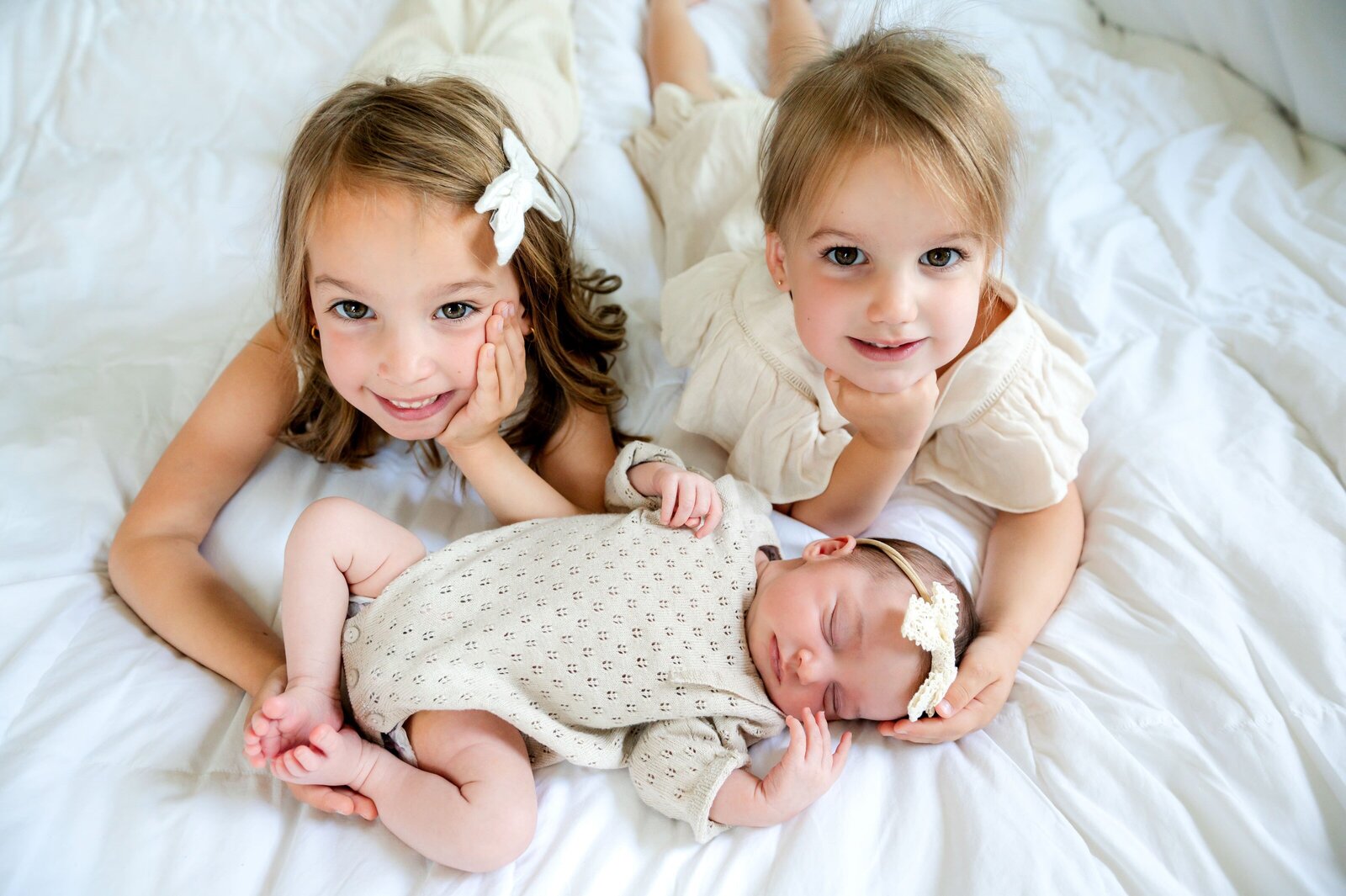 toddler girls laying in bed with their newborn sister