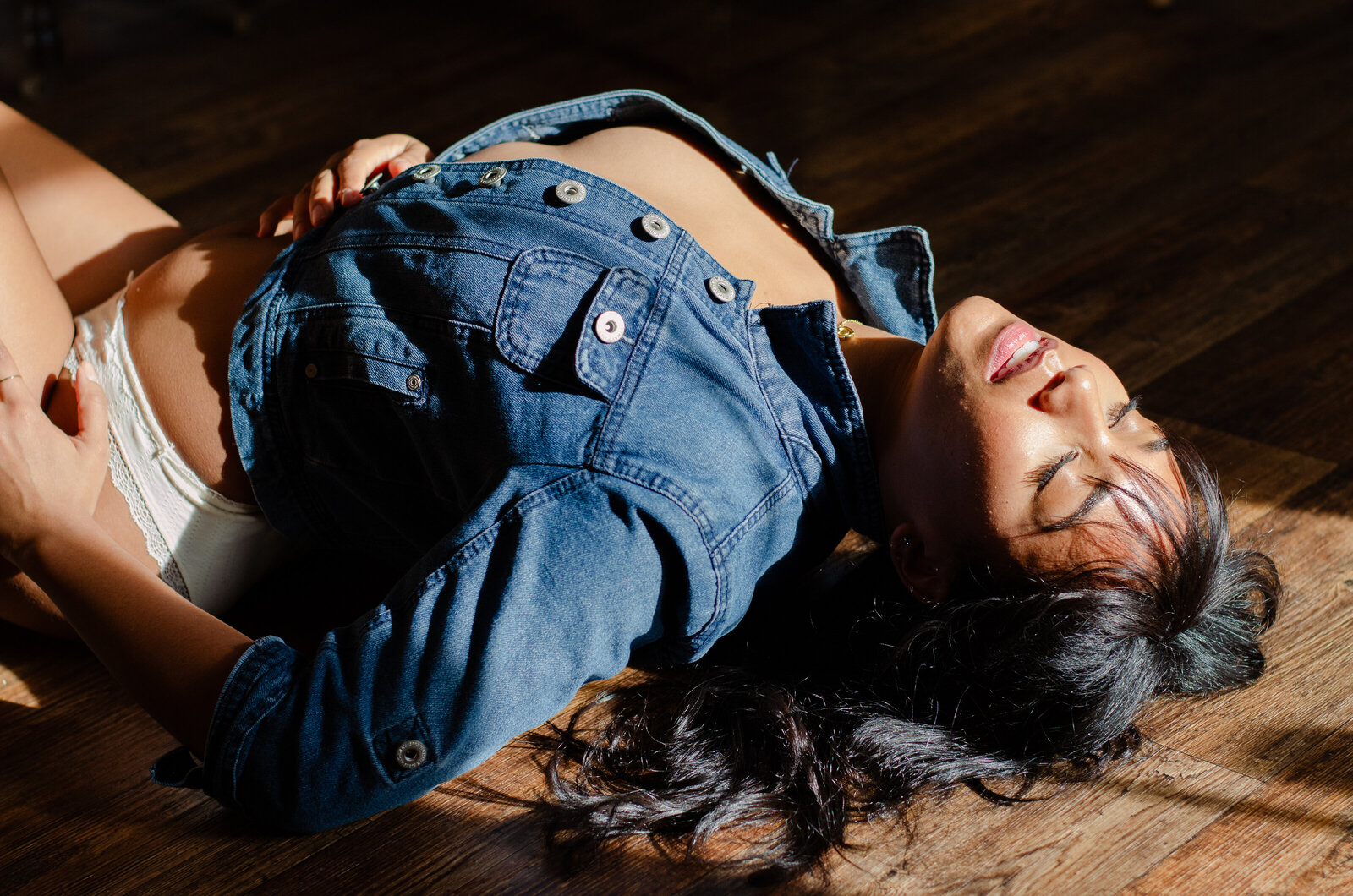 woman in jean jacket on the floor with sunshine hitting her face