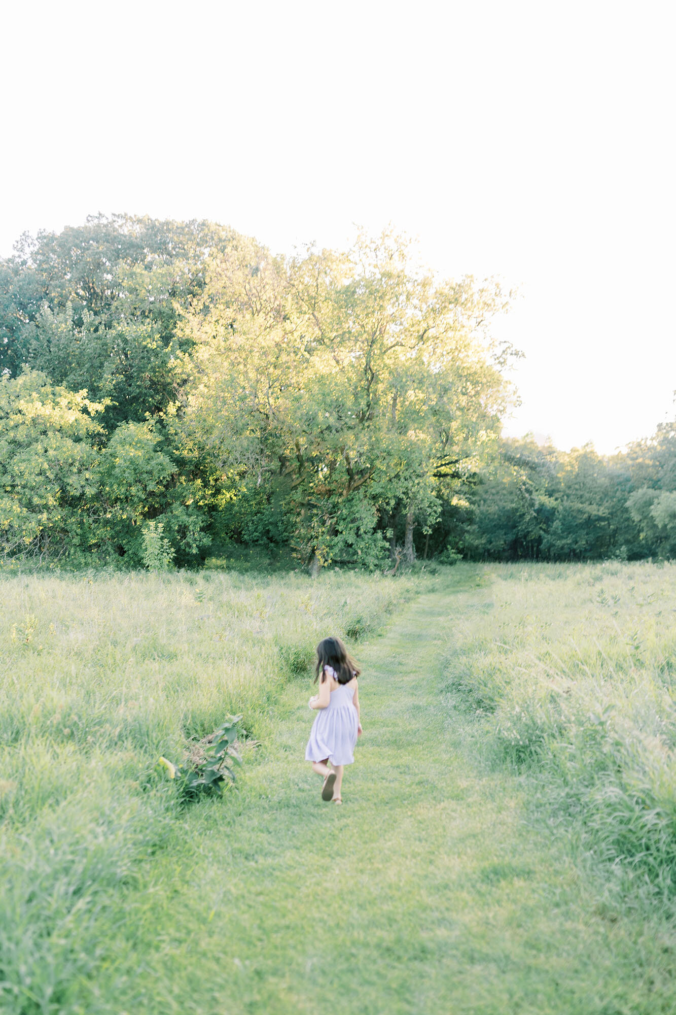A girl running in a field at sunset during her session at Turtle River in Grand Forks