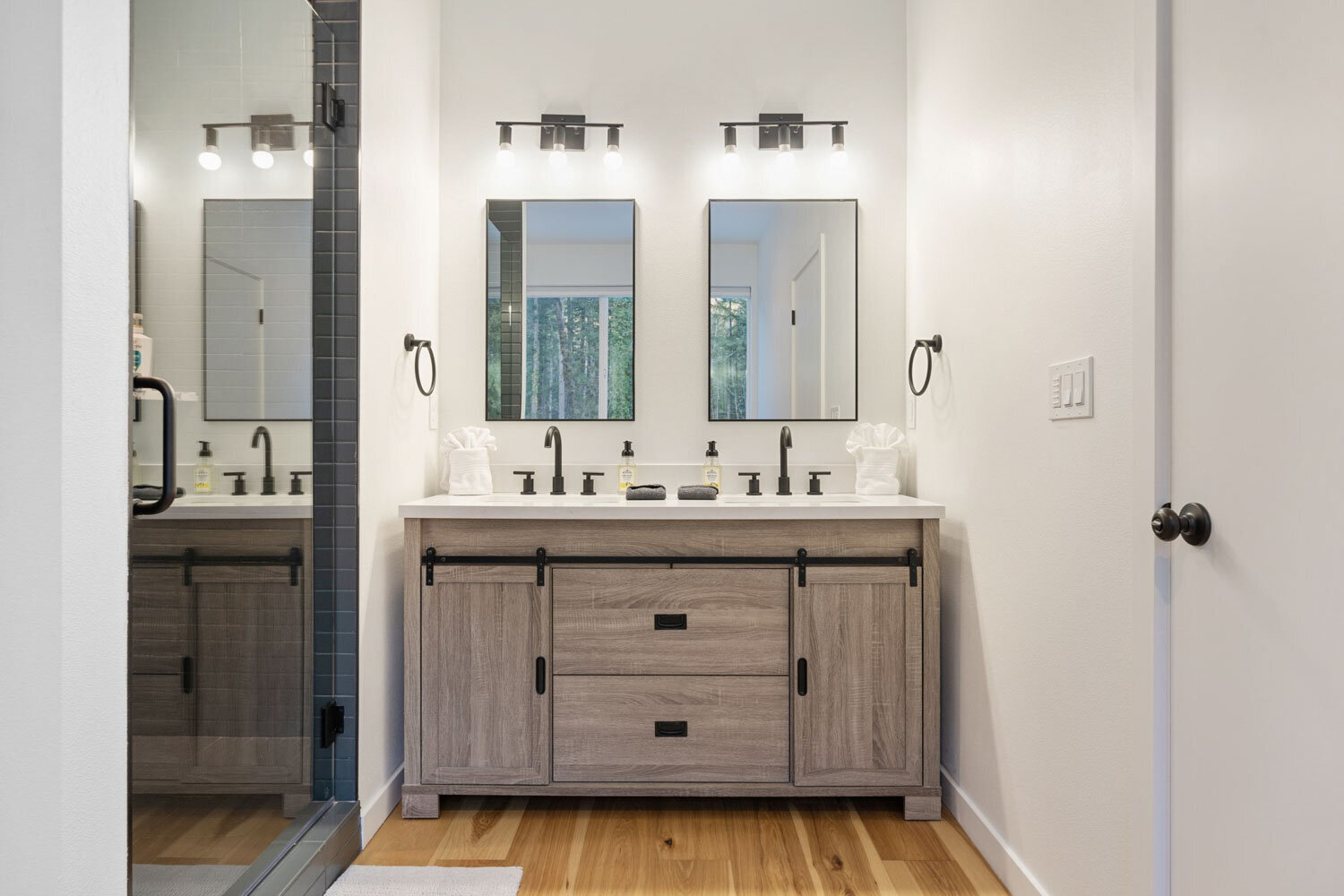 Modern bathroom with double vanity, two mirrors, and black fixtures