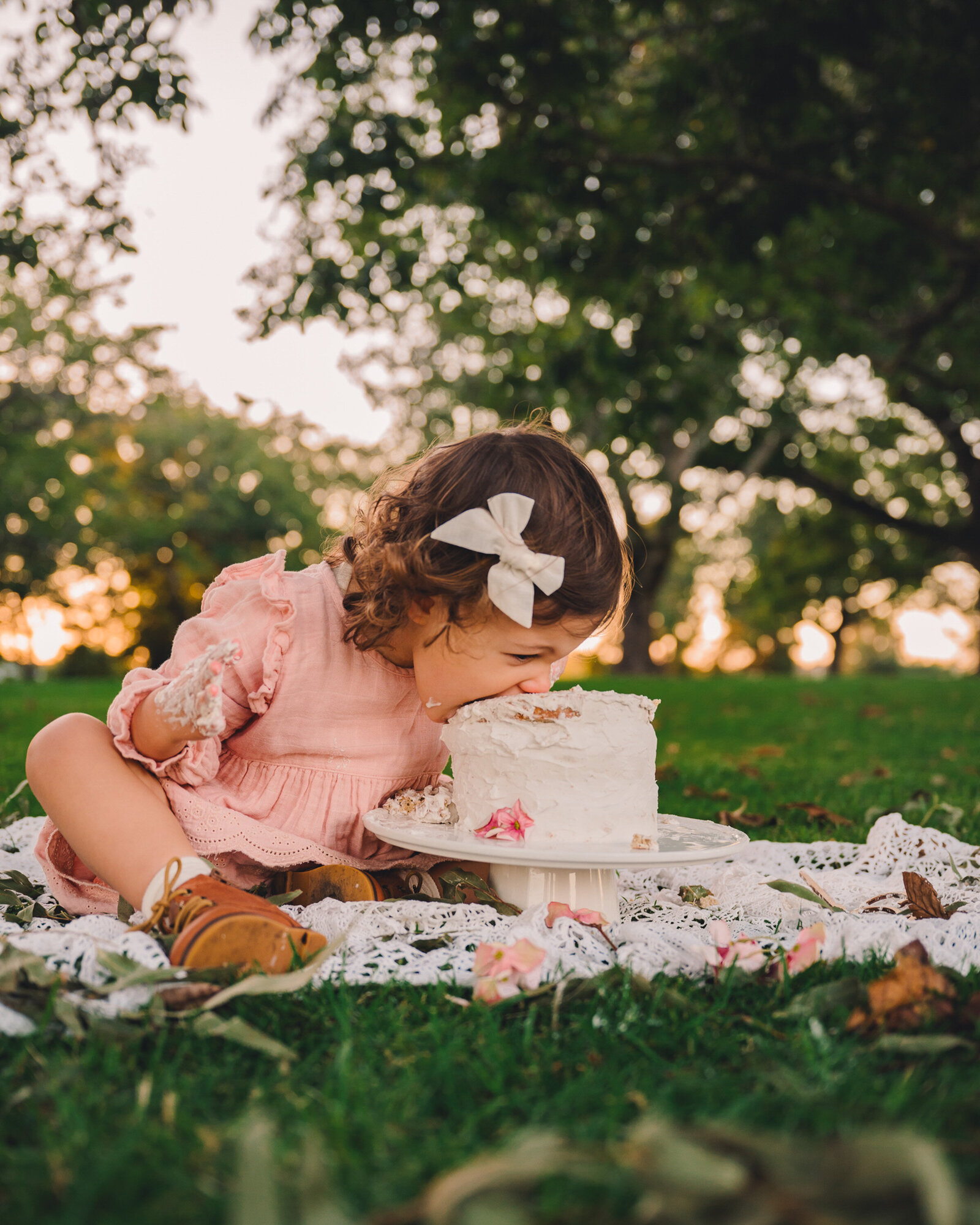 Cake smash photo of a little girl in the setting sun  going face first into the cake